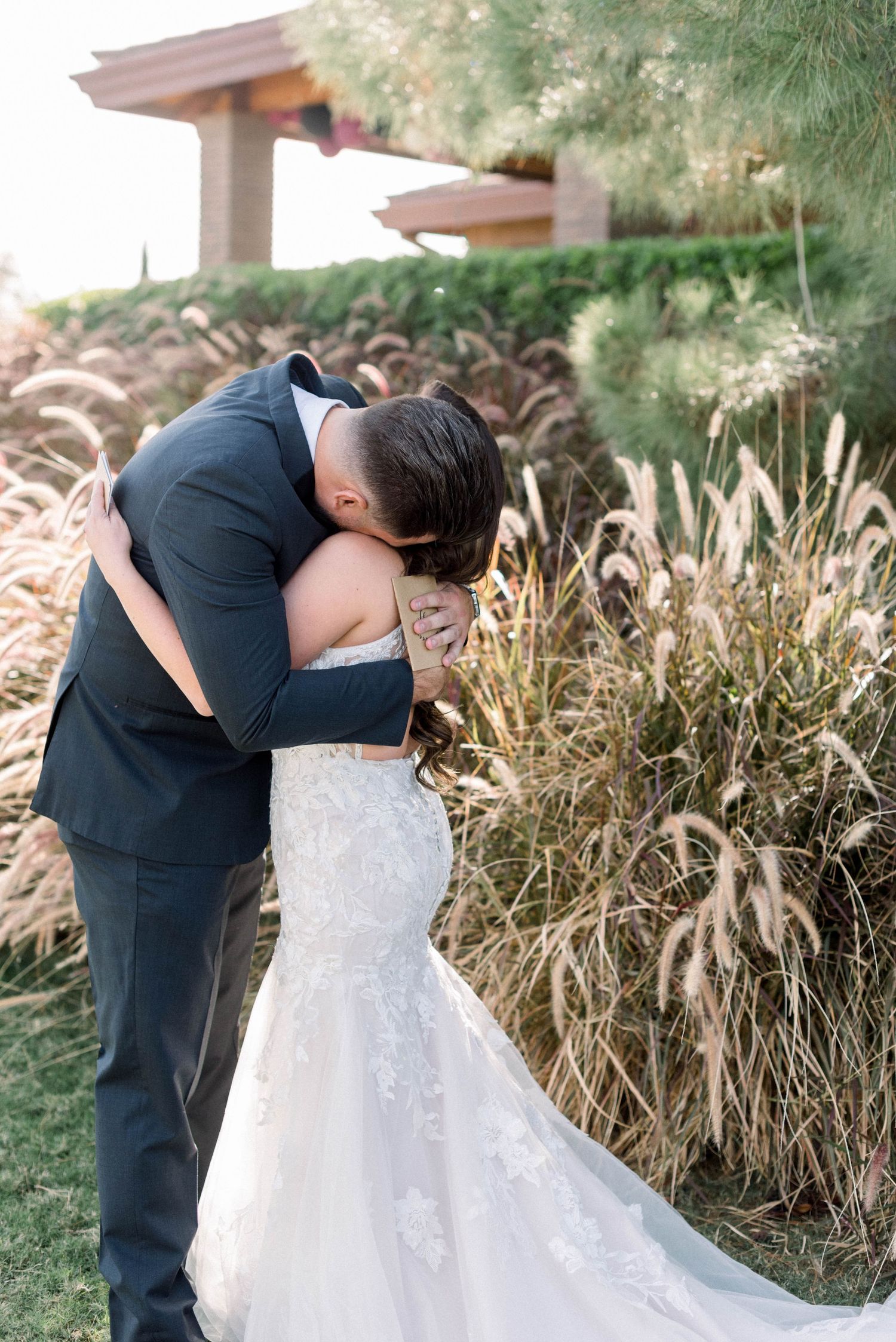 A tender embrace between a couple during their wedding first look surrounded by natural landscaping.
