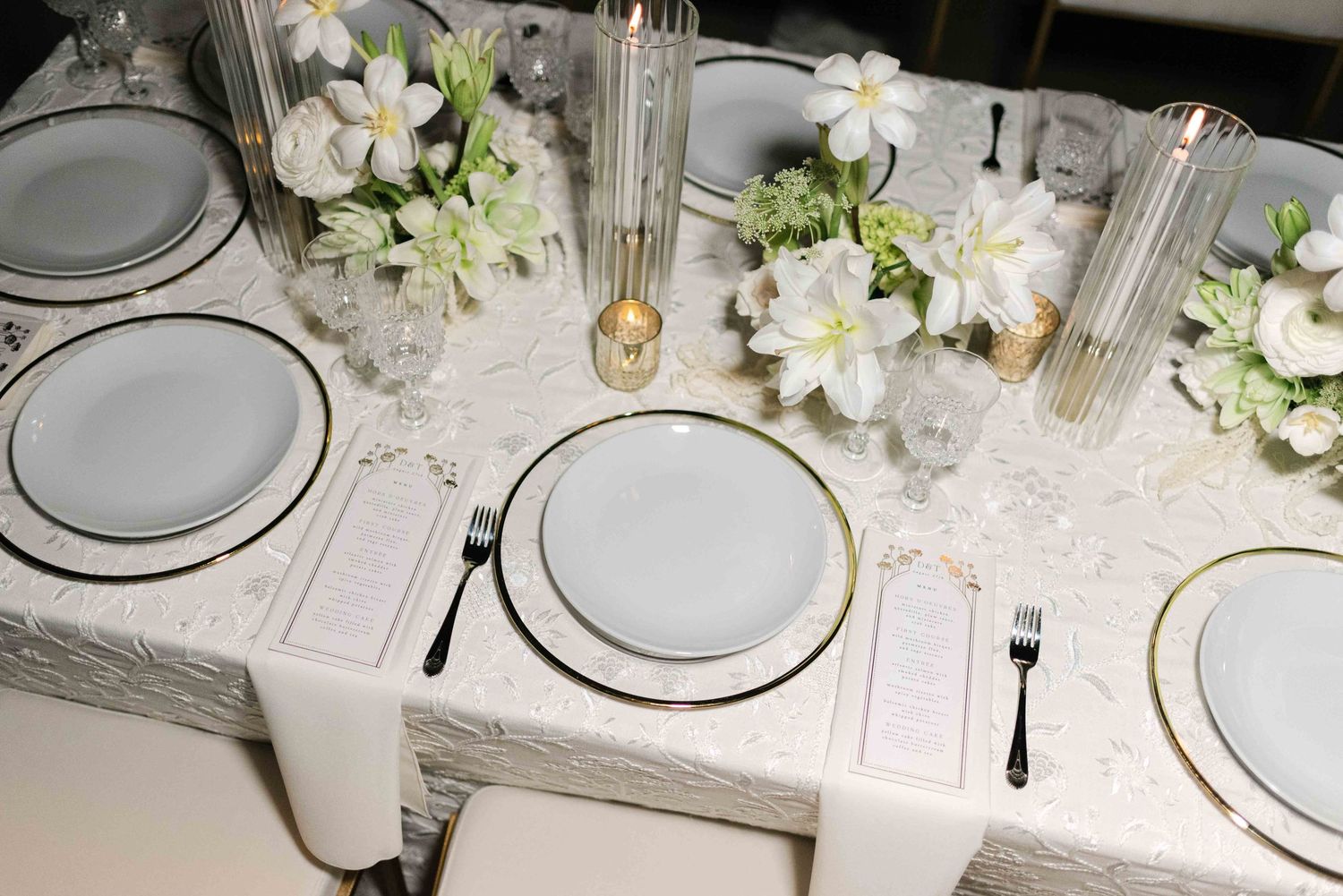 Elegant white wedding table setting with floral centerpieces and crystal glassware.