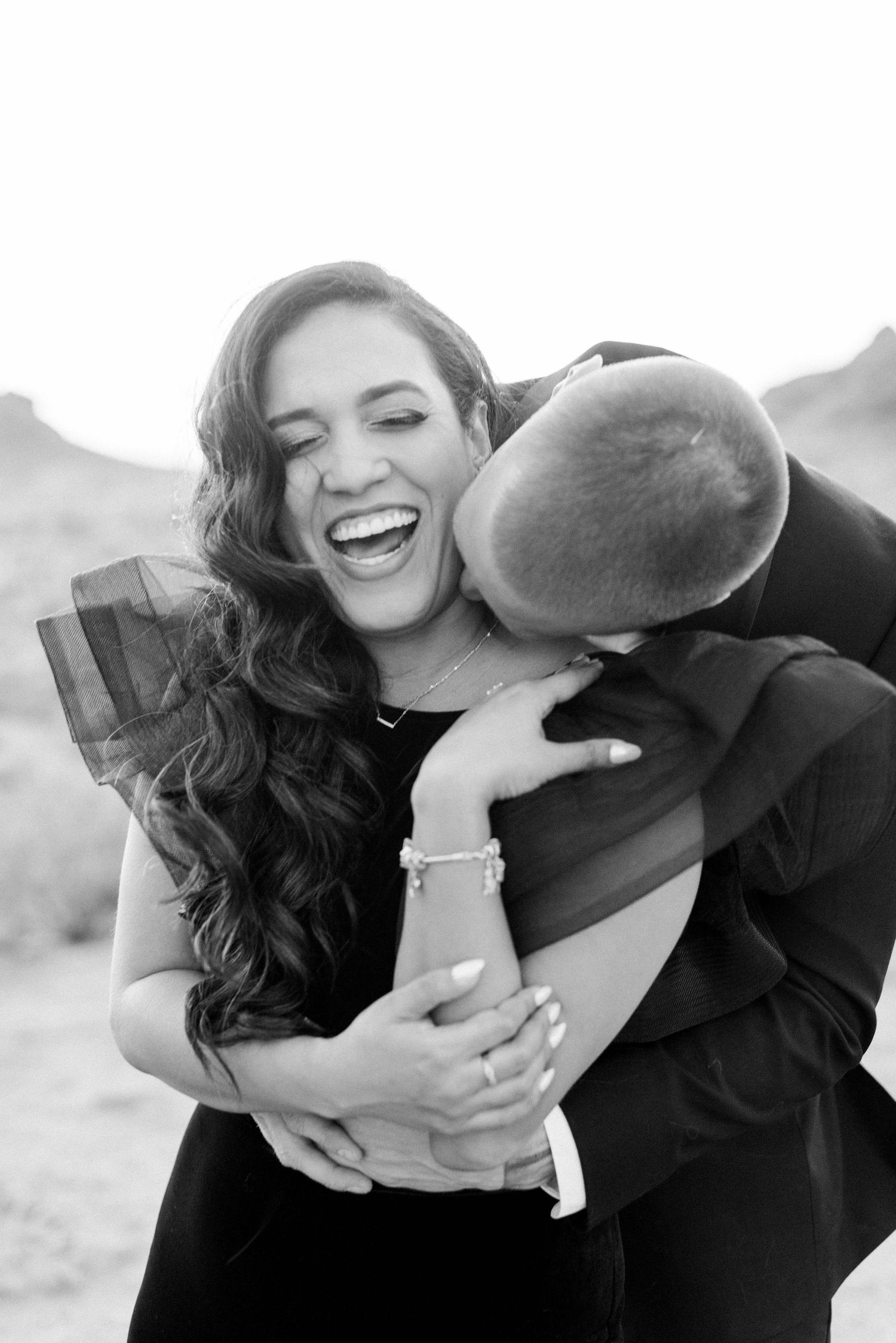Joyful moment captured in black and white during formal desert photoshoot.
