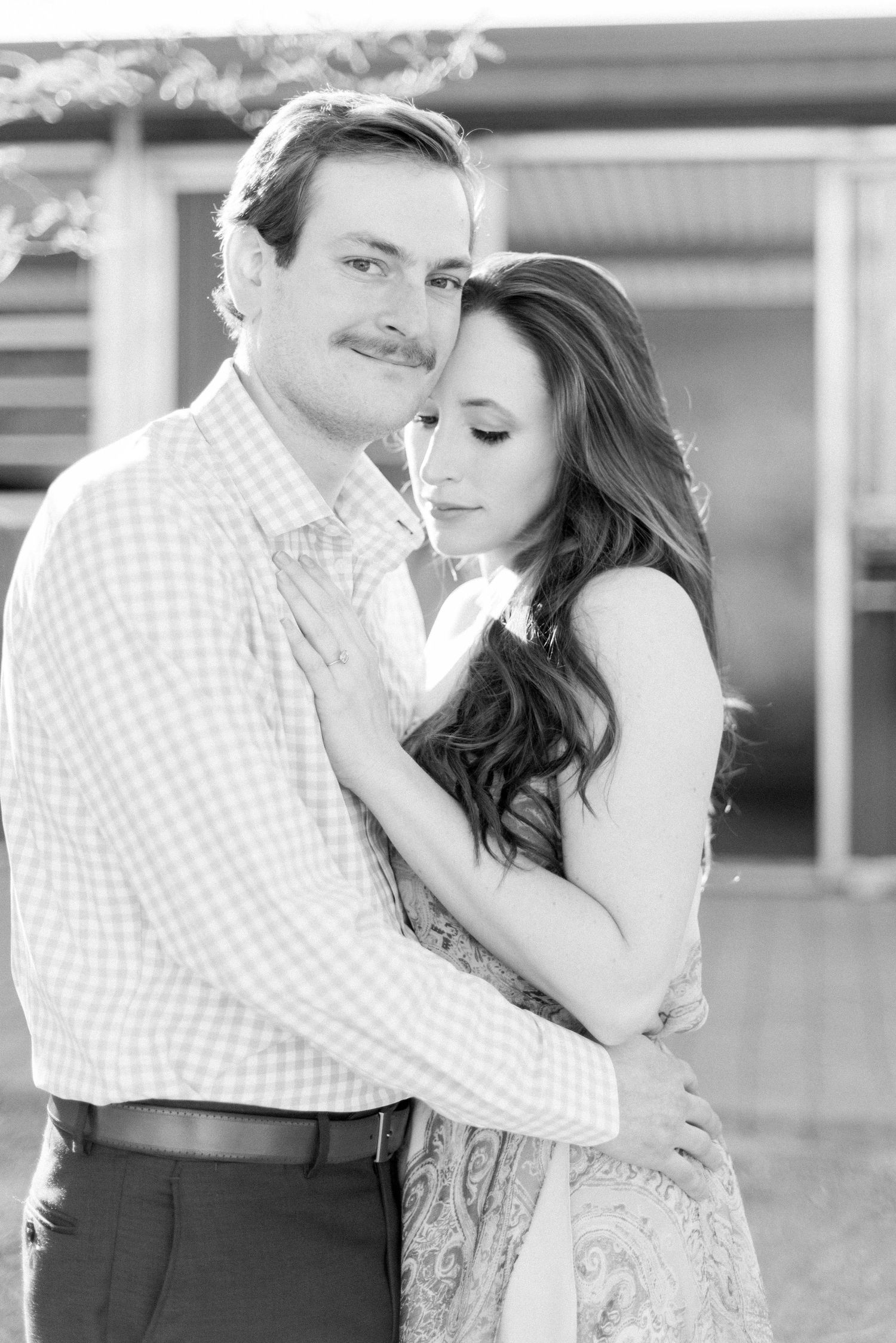Black and white portrait of couple in romantic embrace wearing formal attire.