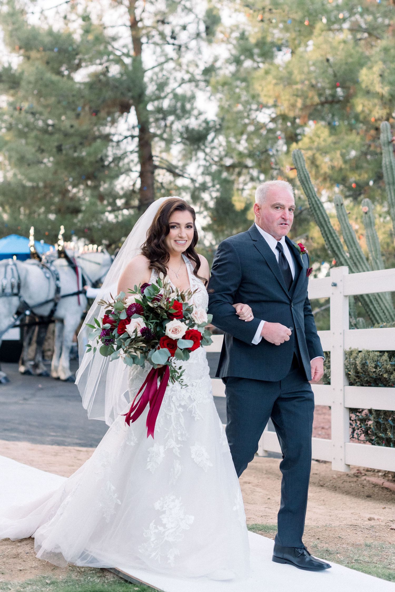 A formal procession down a garden pathway with a white fence and carriage in background.