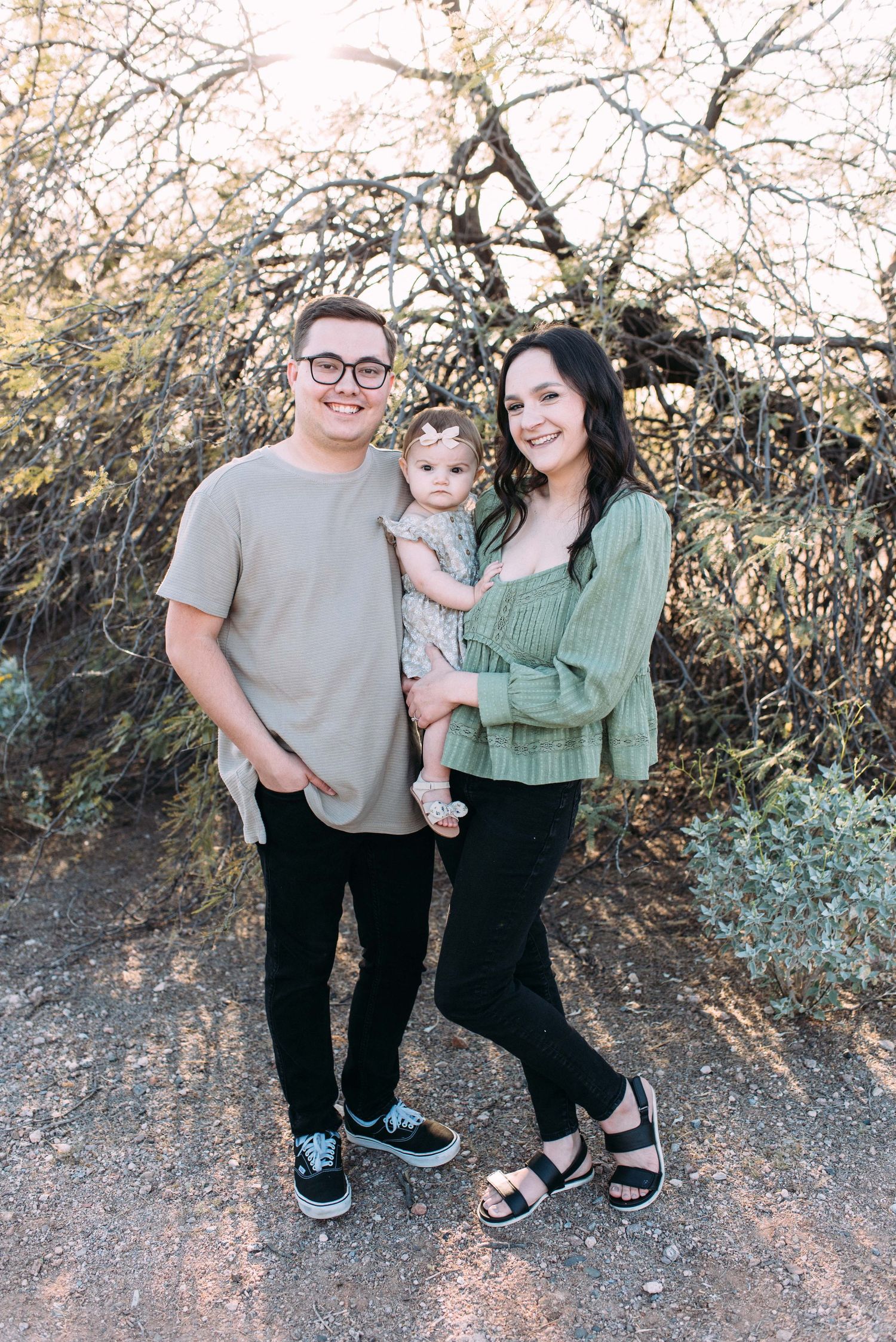 Family poses together on outdoor desert trail during golden hour.
