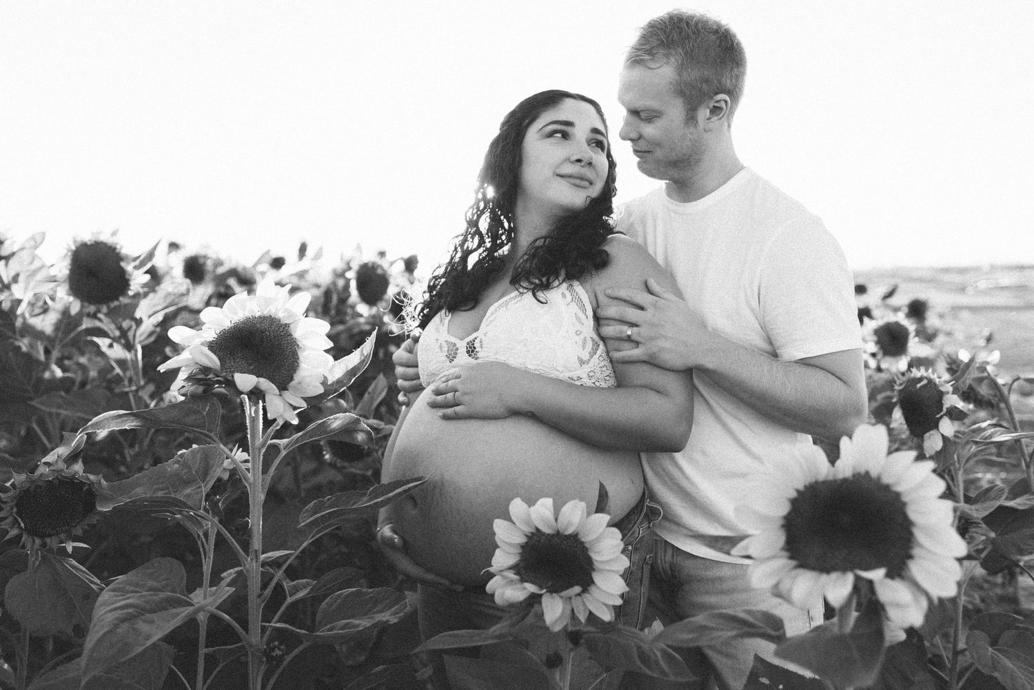 Black and white maternity photo of couple in sunflower field