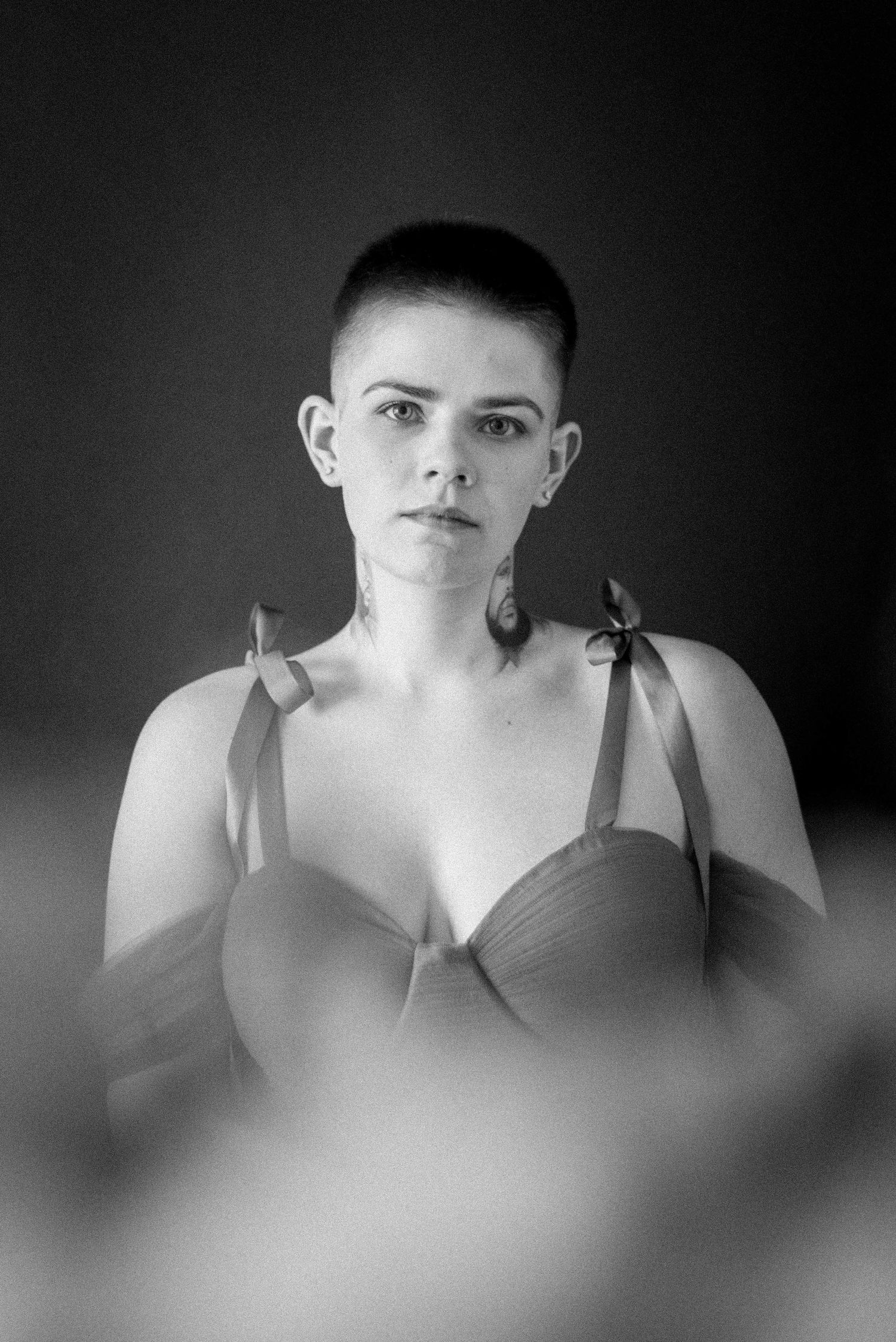 A black and white portrait with soft focus effect against dark background.