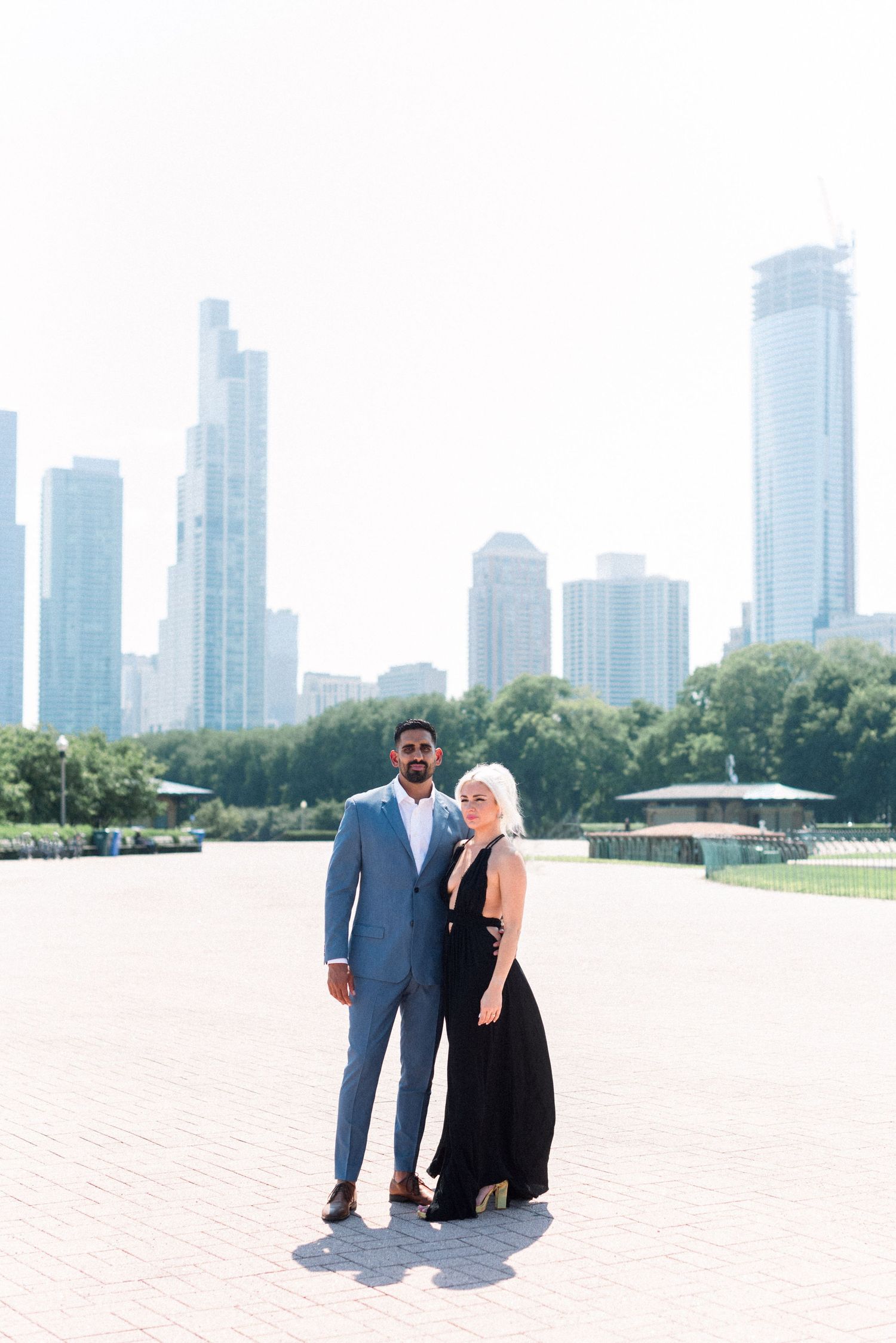 Couple in formal wear posing against Chicago skyline background near Buckingham Fountain.