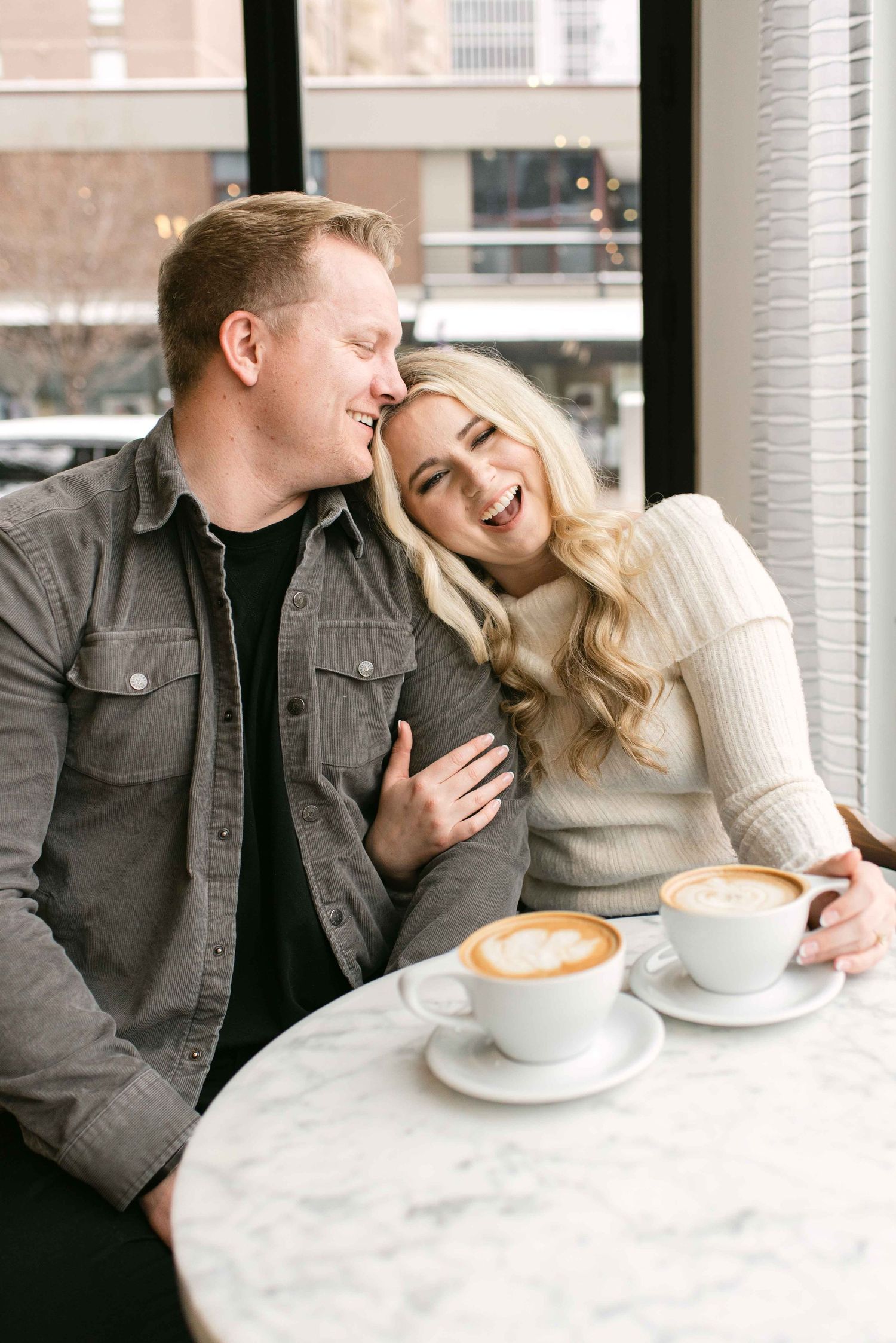 Joyful couple laughing together during coffee date at city cafe.