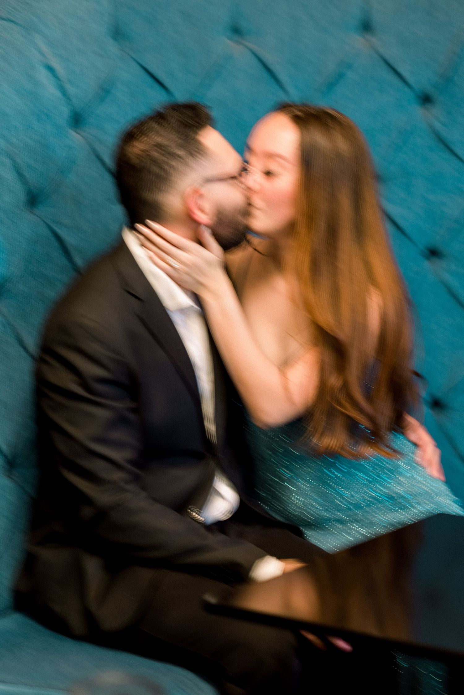 Romantic couple sharing an intimate moment against a tufted blue velvet backdrop.
