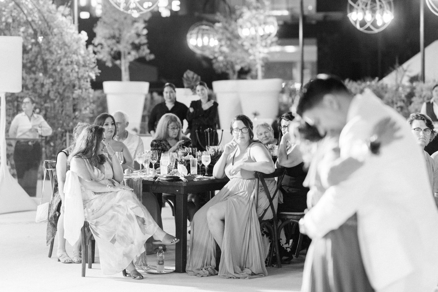 Wedding guests seated at tables watch as a couple dances during their reception.