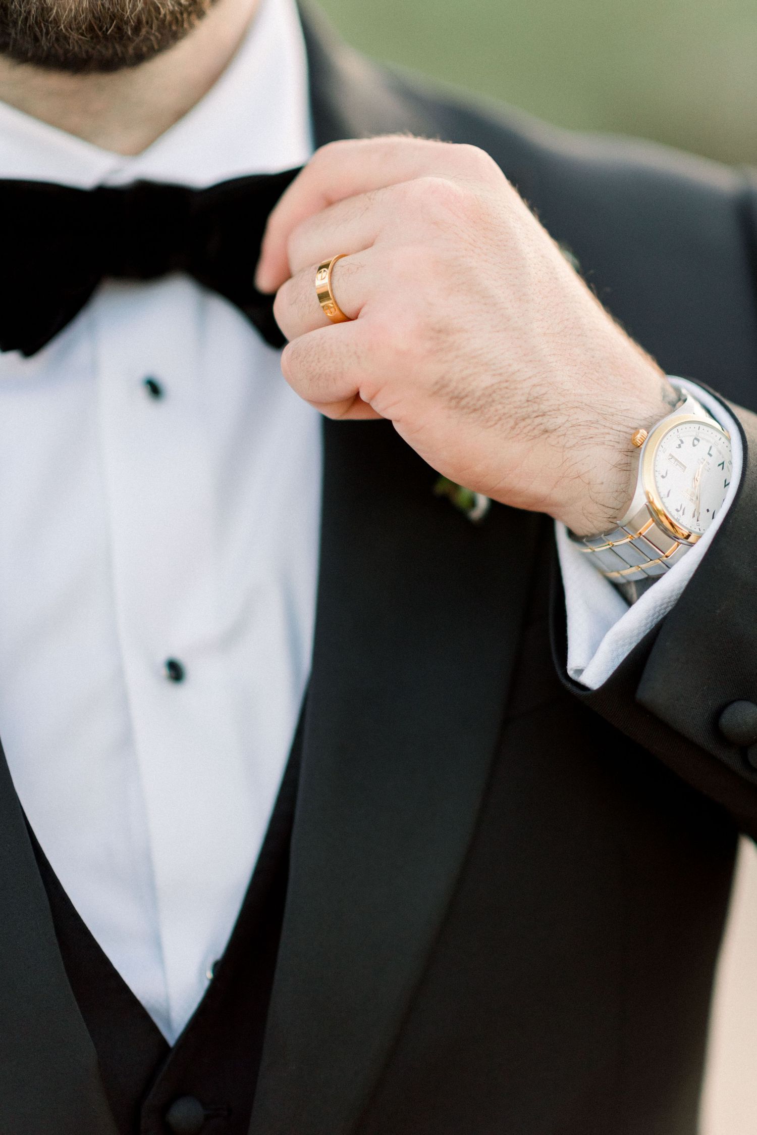 Close-up details of a groom's formal attire showing cufflinks and watch accessories.
