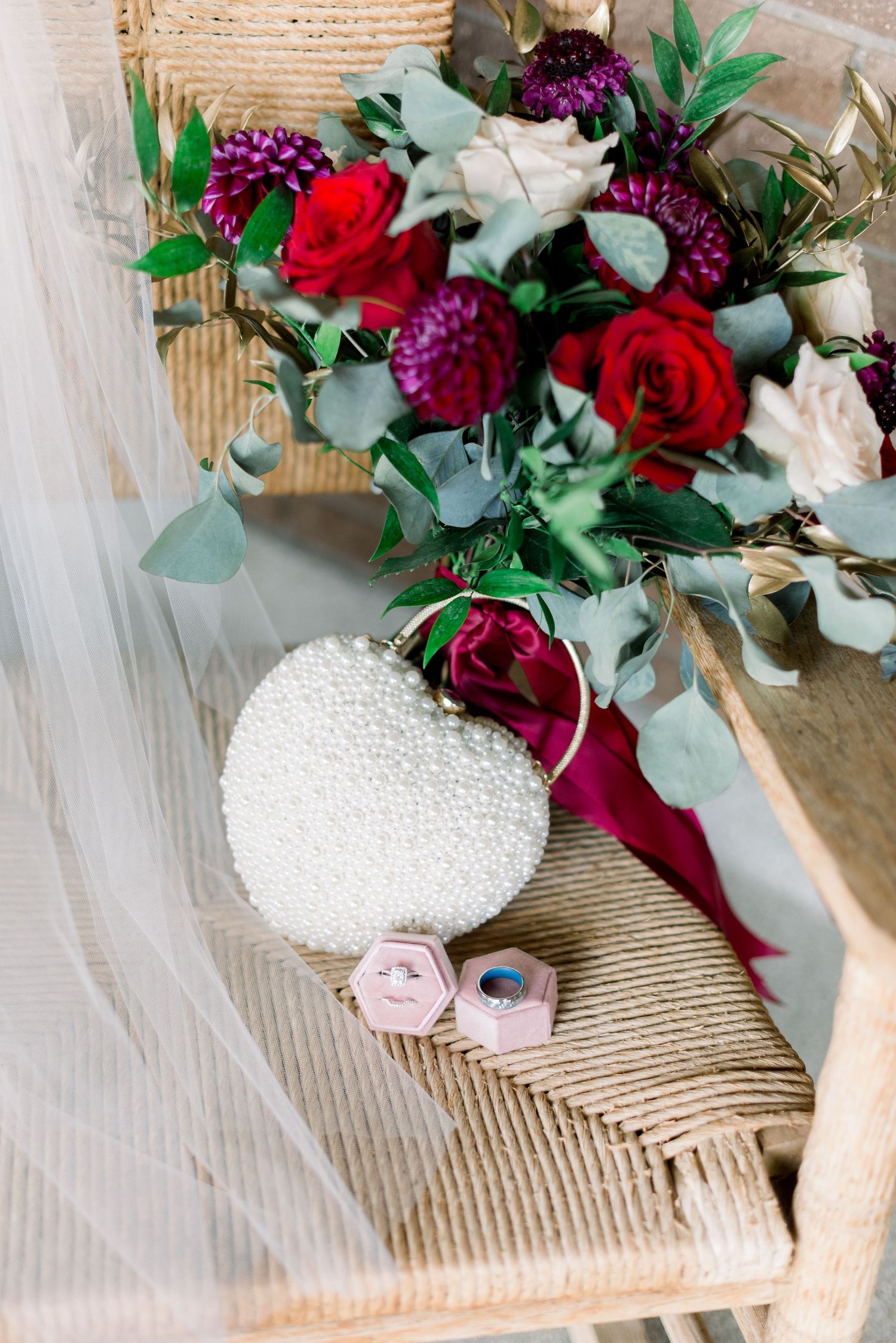Floral arrangement with red roses and pearl decoration on wicker furniture.