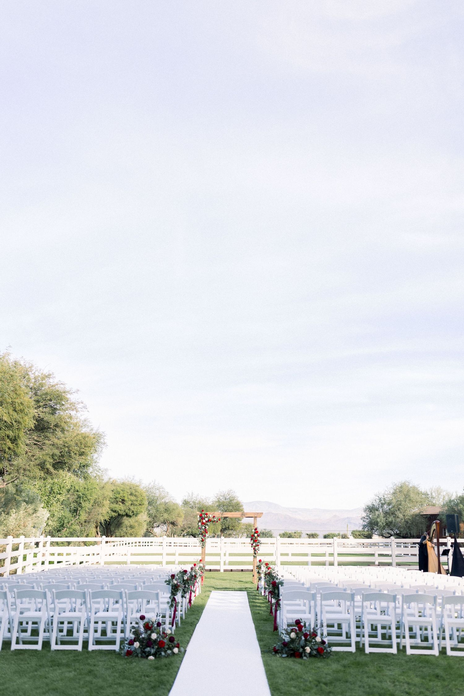 Outdoor wedding ceremony setup with rows of white chairs and a white aisle runner against a scenic backdrop.