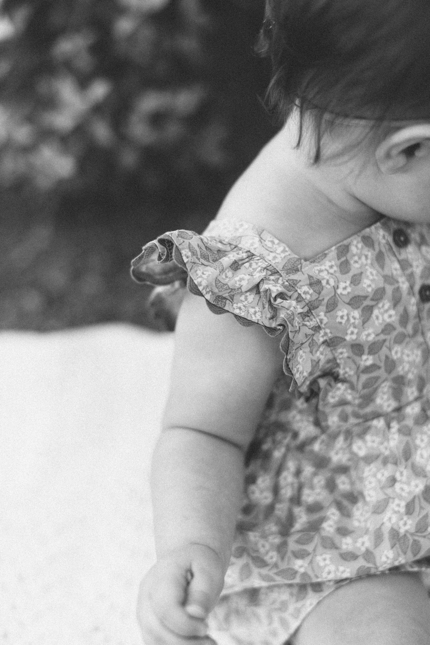 Black and white close-up of ruffled sleeve detail on floral baby dress.