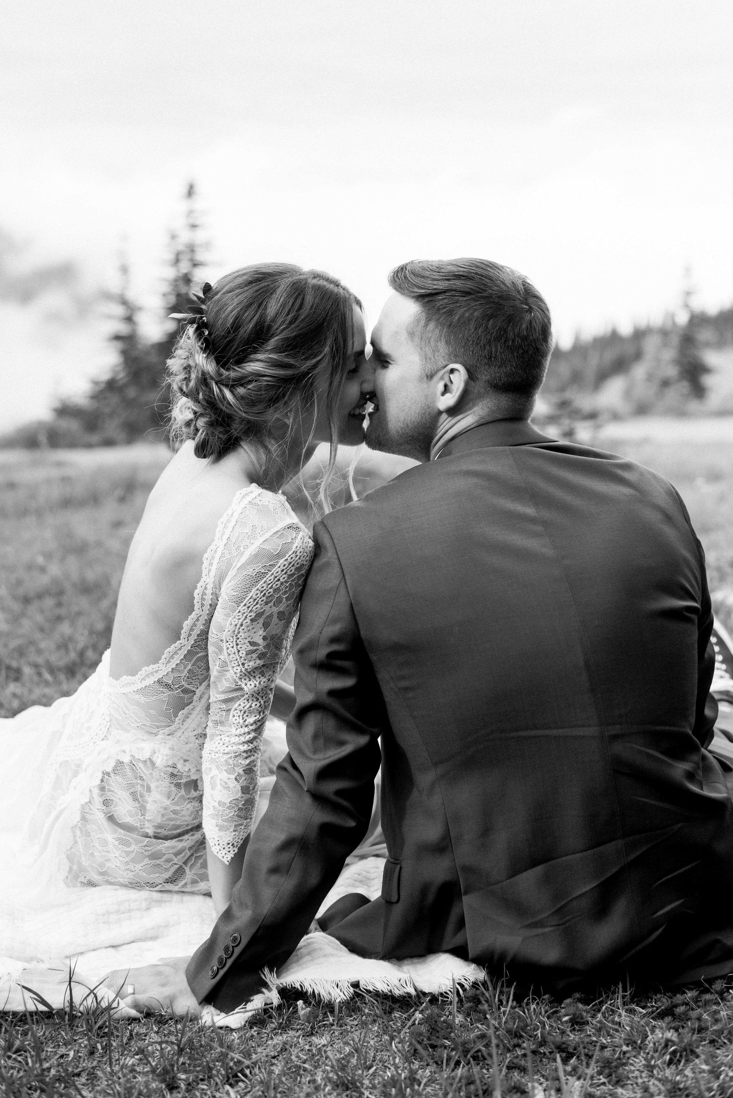 Intimate black and white portrait of couple sitting in mountain meadow.