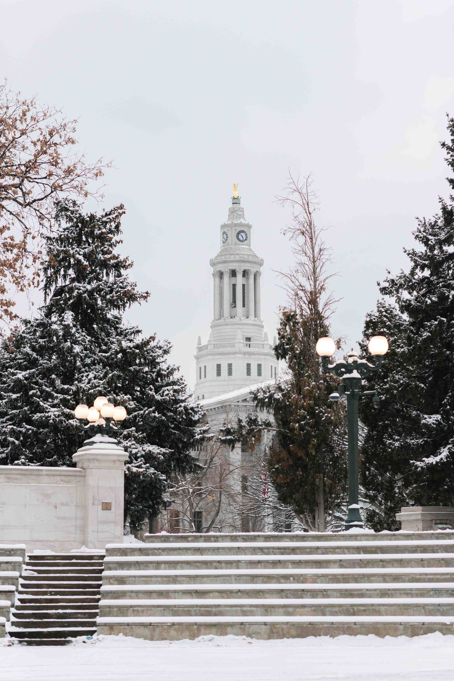 Snow-covered church steeple with clock tower rises above winter landscape.