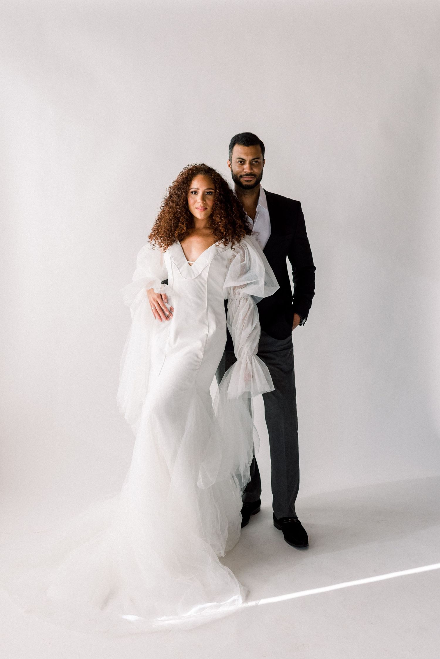 A romantic wedding photo featuring a couple in formal attire against a light backdrop.