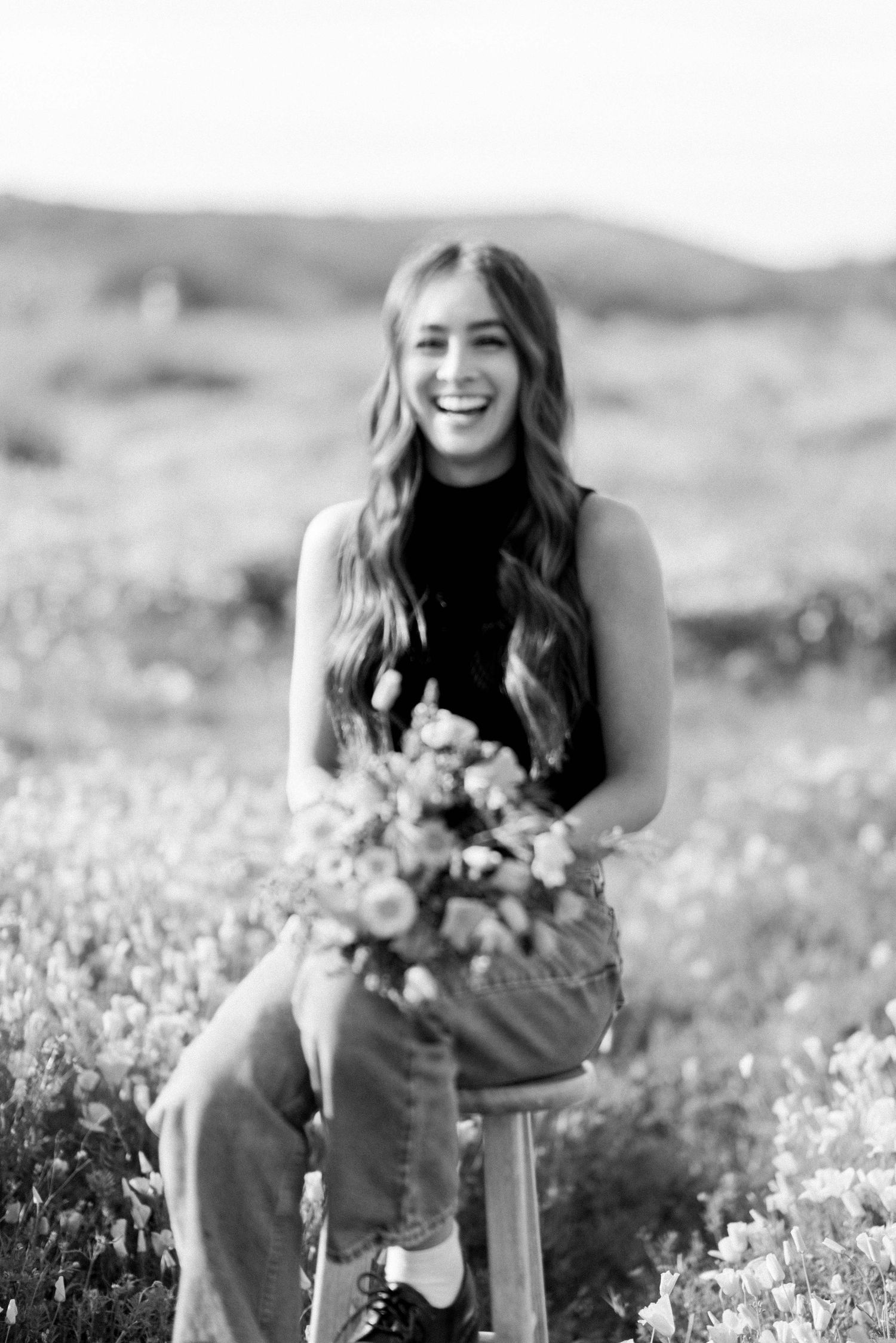 Black and white portrait with flowers in a natural meadow setting.