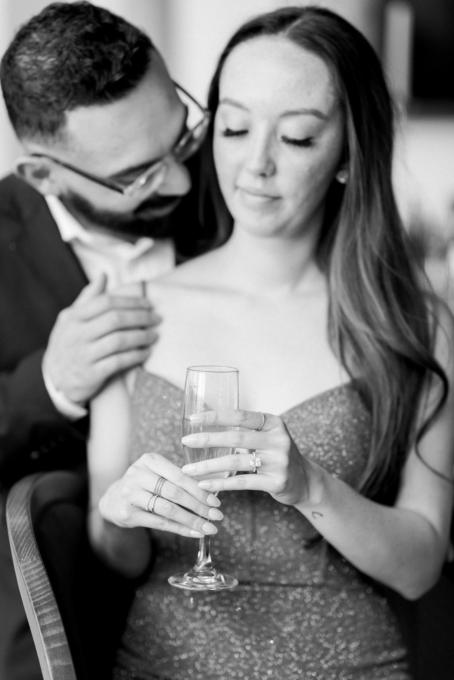 Black and white intimate portrait of a couple sharing drinks in formal attire.