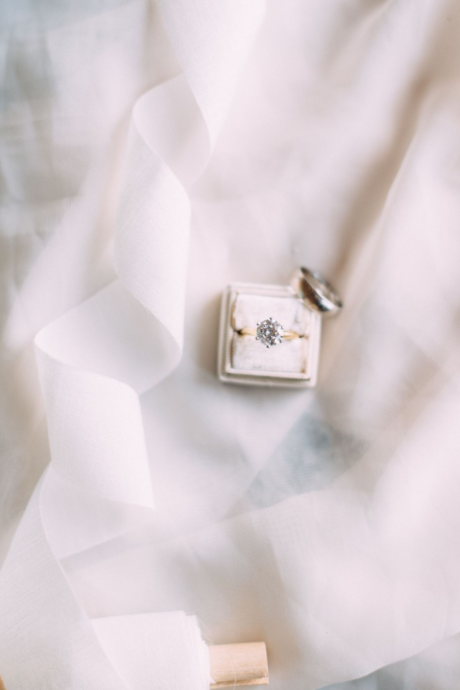 A sparkling diamond engagement ring nestled in a white velvet ring box.