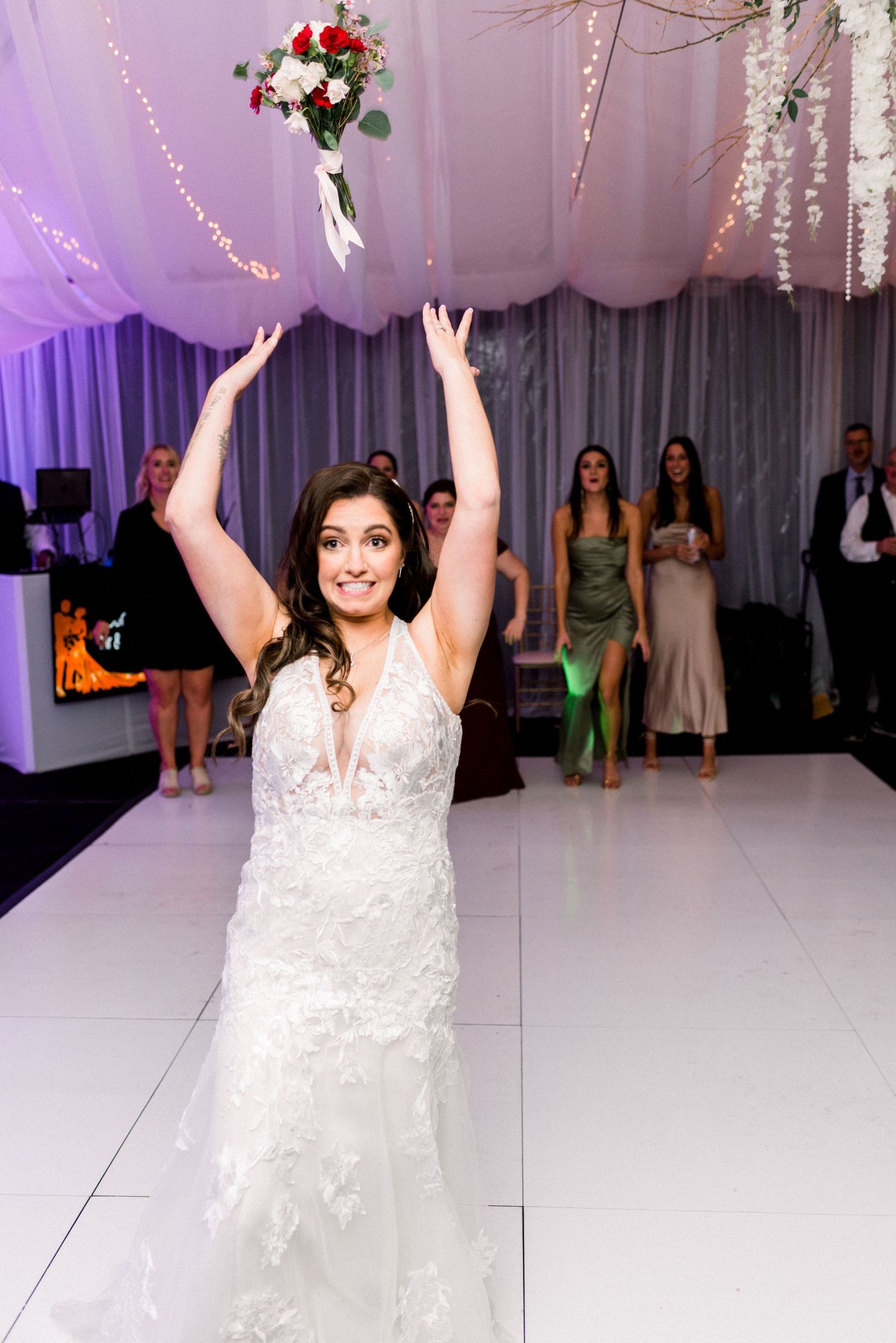 Bride joyfully tossing her bouquet during the traditional wedding reception ceremony.