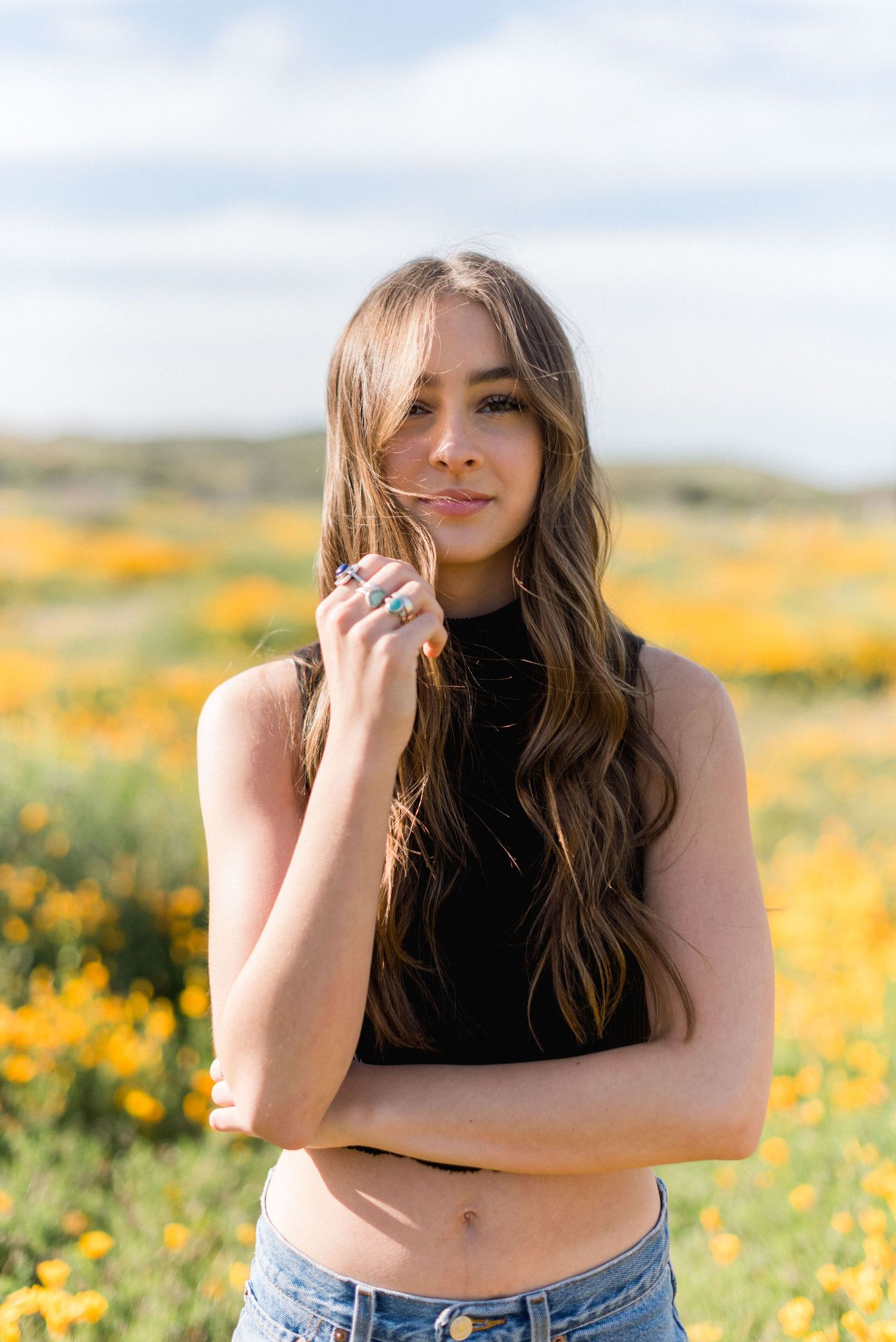 A portrait in black crop top against a backdrop of golden wildflowers.