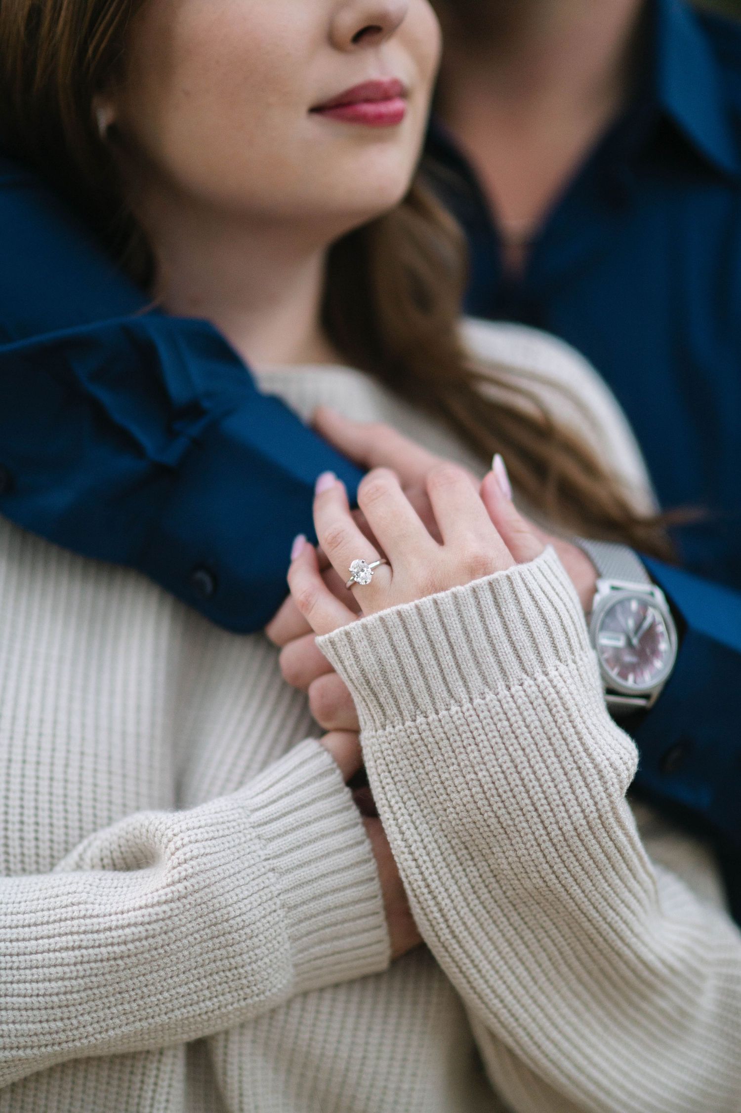 Close-up of hands wearing a cream knit sweater with sparkling ring detail.