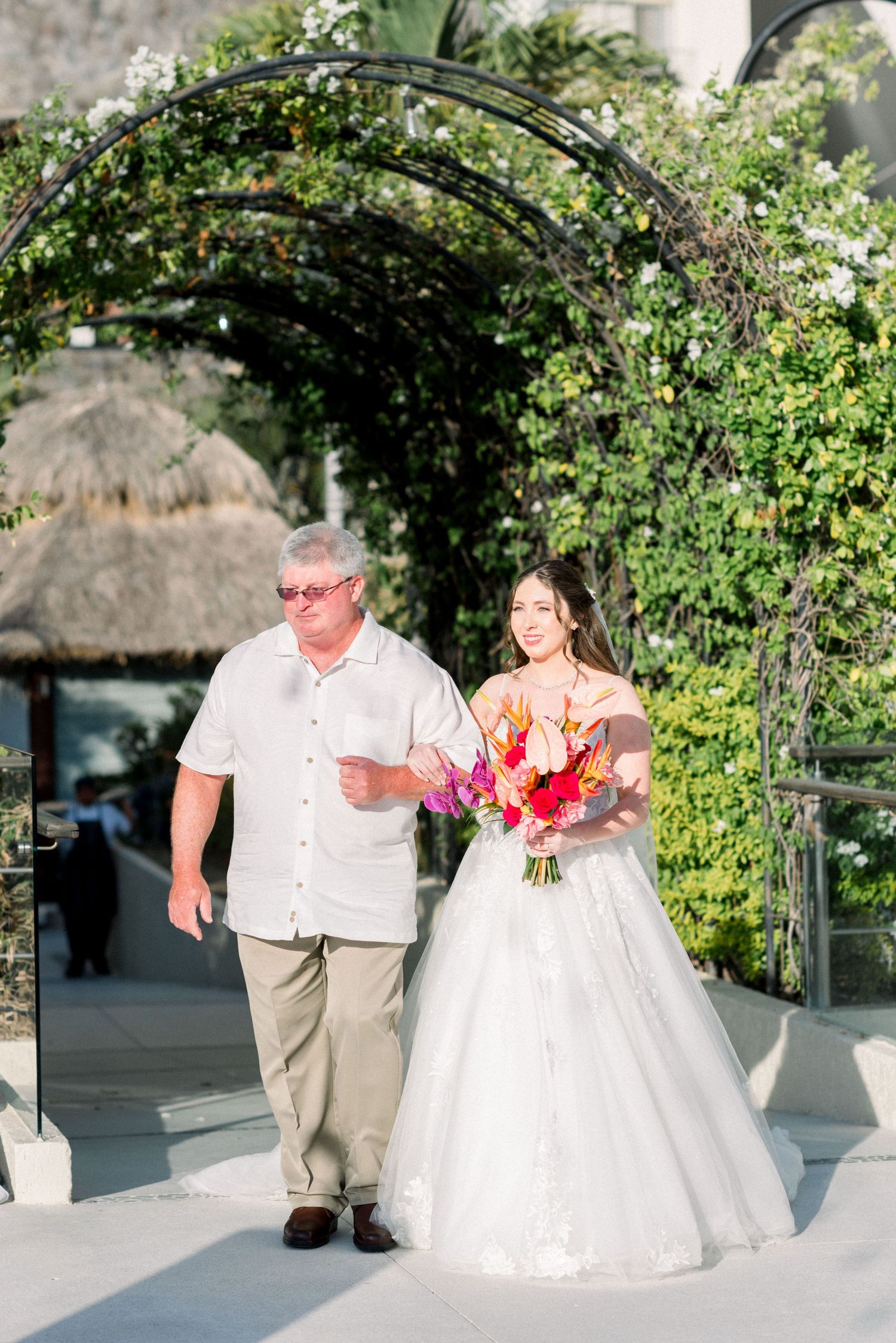 Wedding ceremony entrance under an ivy-covered archway at an outdoor venue.