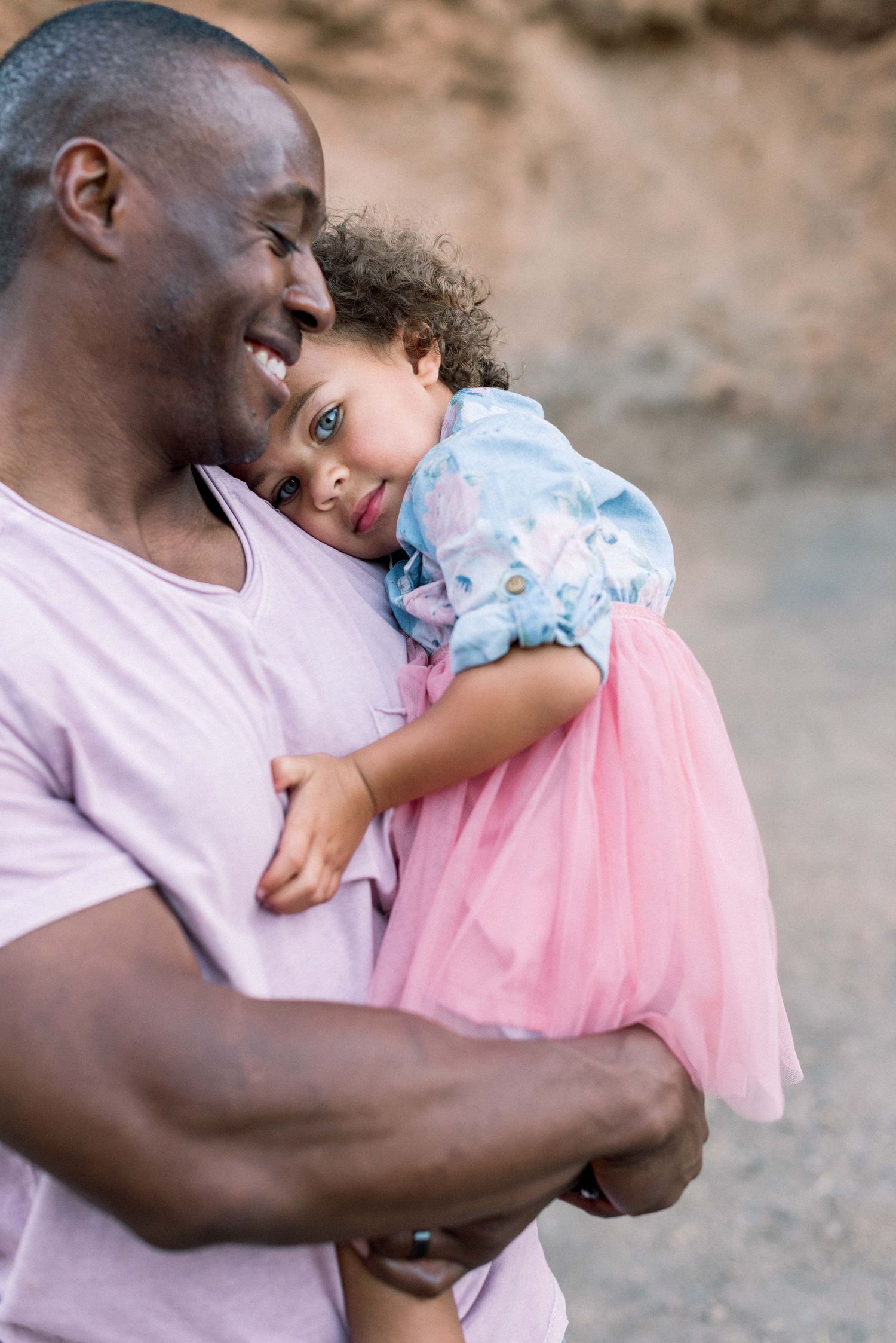 A tender moment captured between two people sharing a warm embrace against a desert background.