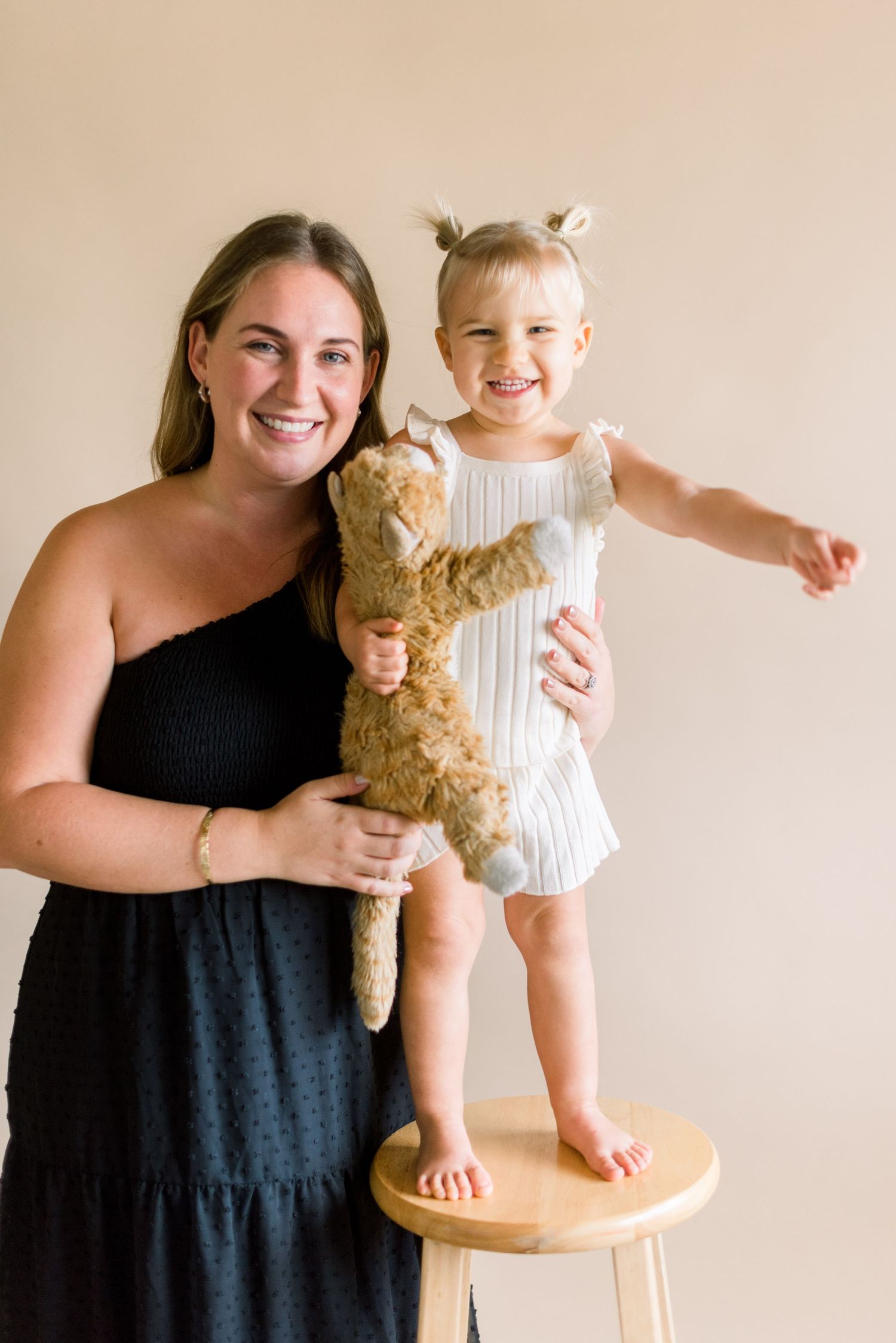 A loving portrait with two people posing together while holding a plush teddy bear.