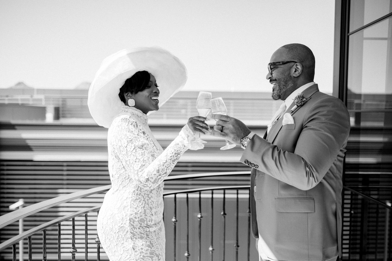 A romantic black and white photo showing a couple giving a cheers together on a balcony.