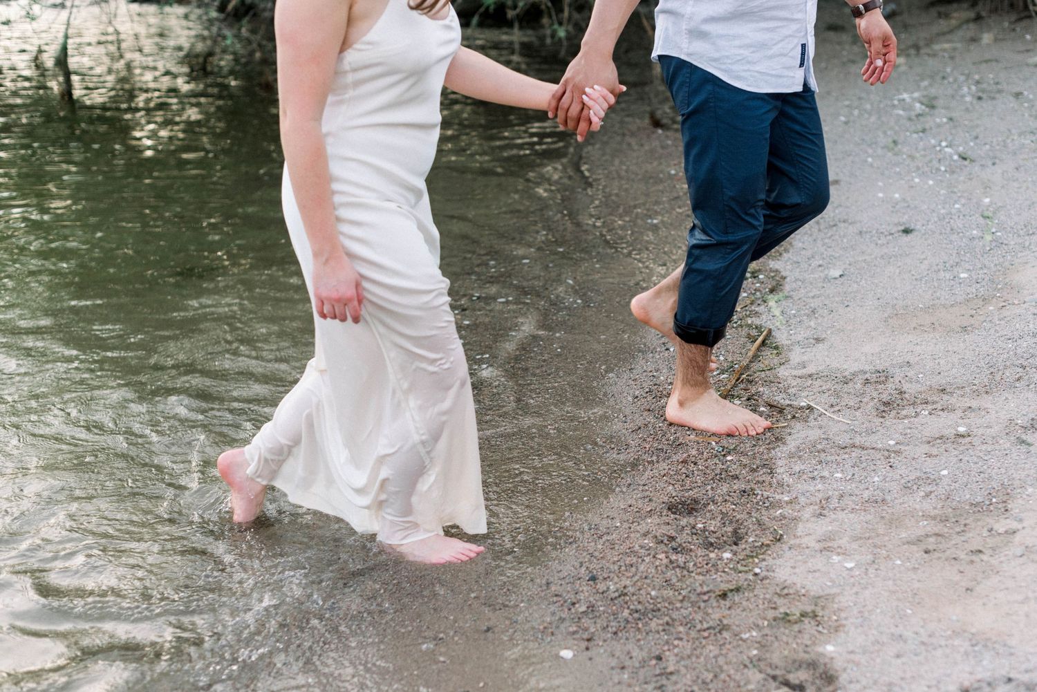 Candid shot of couple's feet and legs walking along the water's edge.