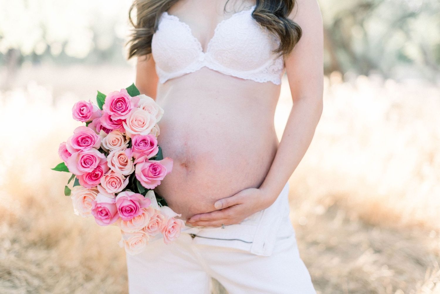 Beautiful pink rose bouquet held in outdoor maternity photo session.