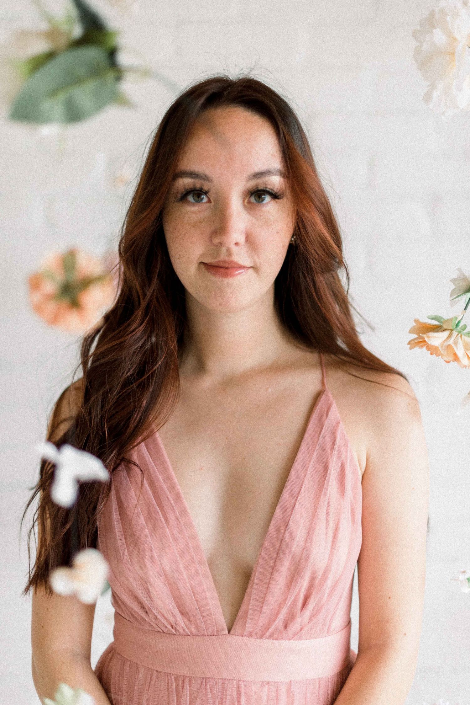 A romantic portrait with floating flowers against a white brick wall background.