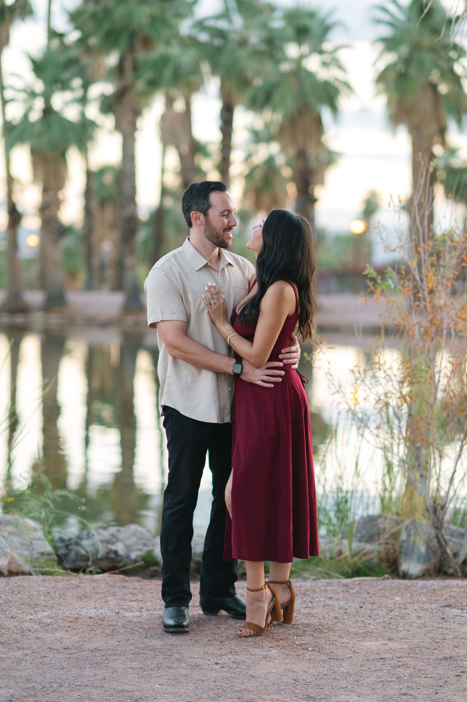 Couple shares romantic moment near palm trees at sunset in desert setting.