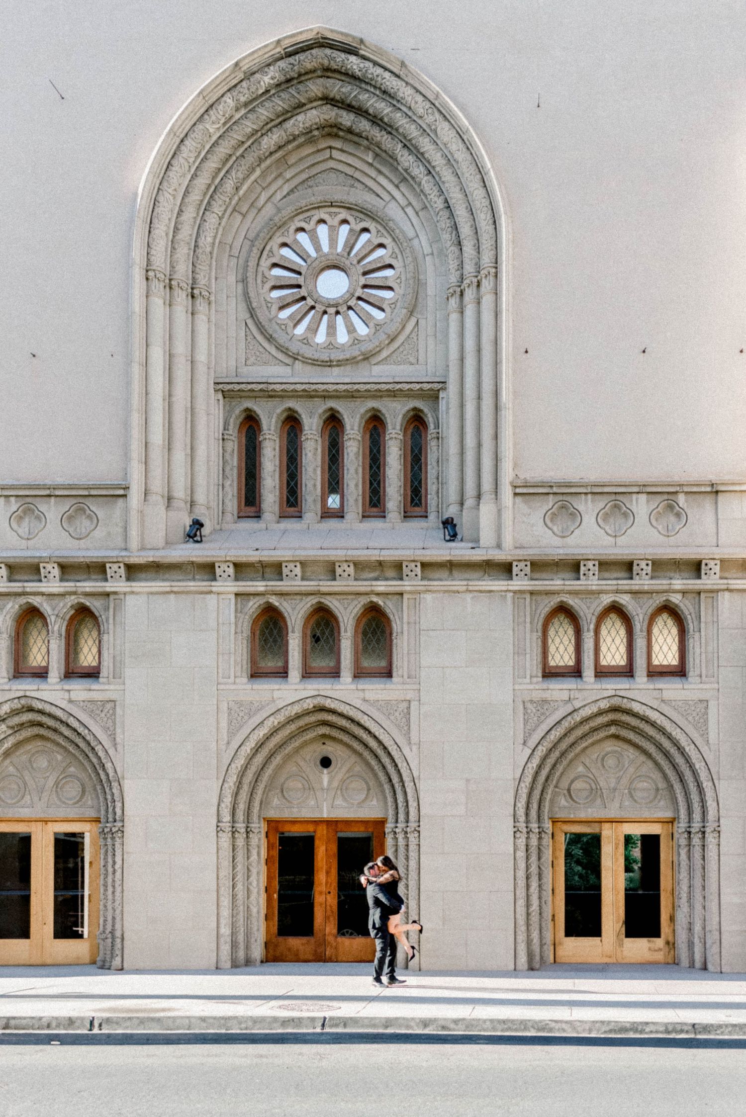 Gothic-style church facade with arched doorways, ornate rose window, and architectural details in white stone.