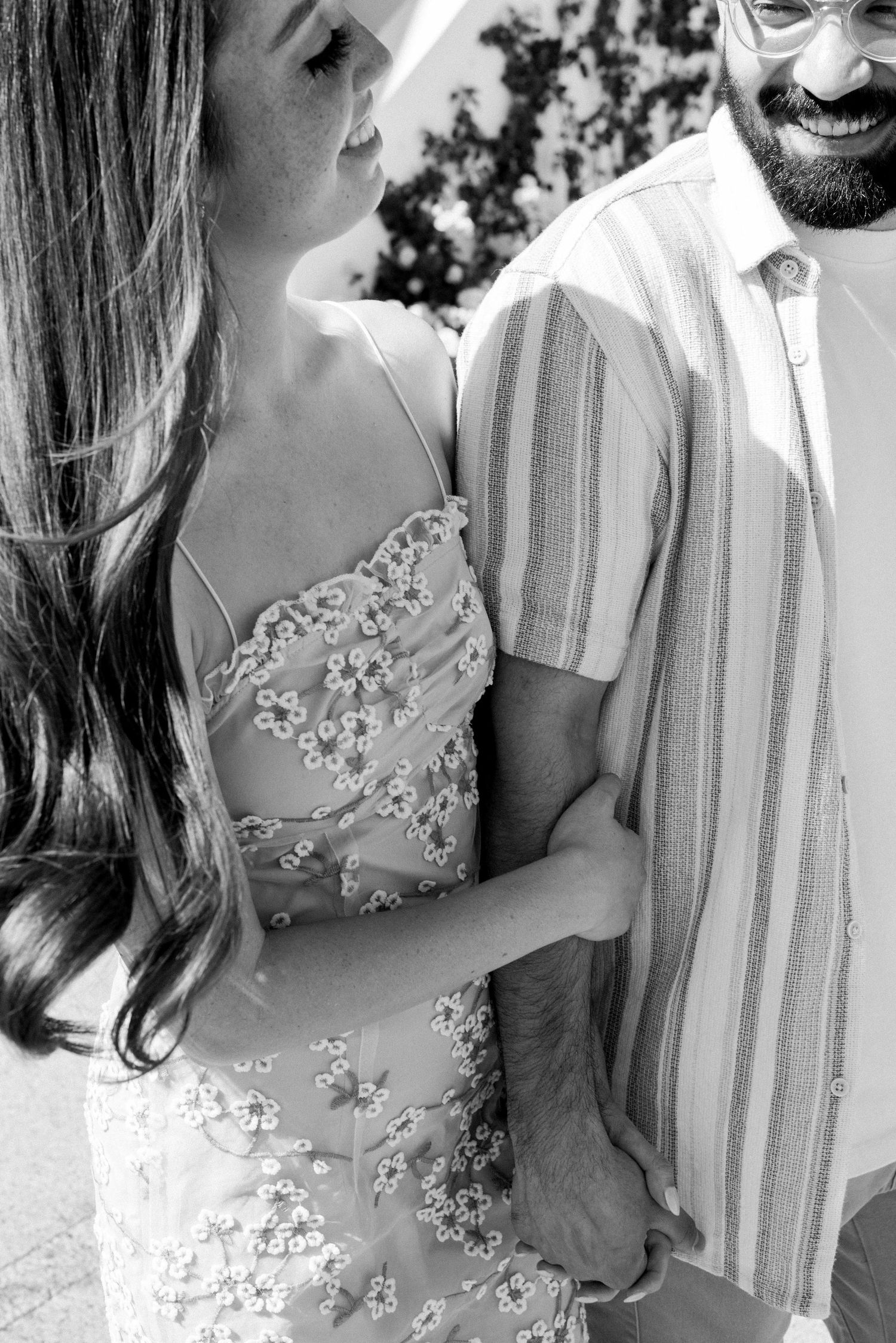 Black and white detail shot of couple in formal attire with embellished dress and striped shirt.