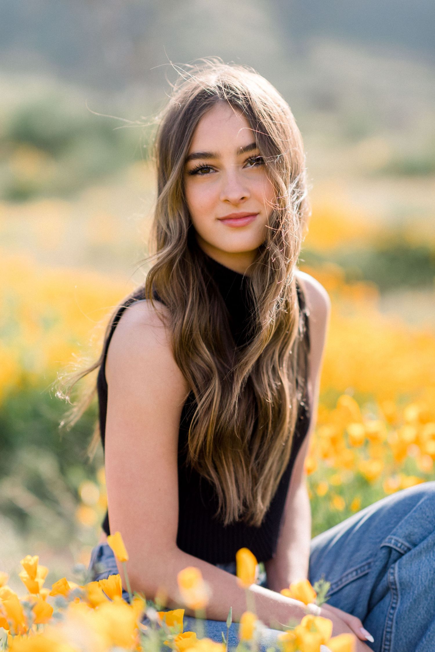 A portrait in a field of golden wildflowers on a sunny afternoon.