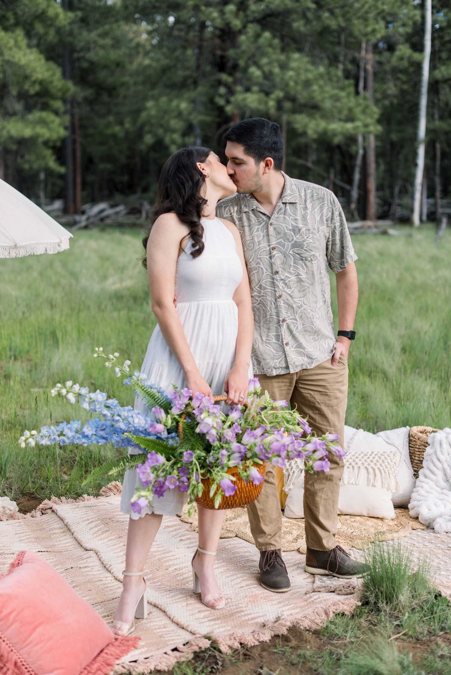 Romantic couple sharing a kiss in a dreamy outdoor setting with purple wildflowers.