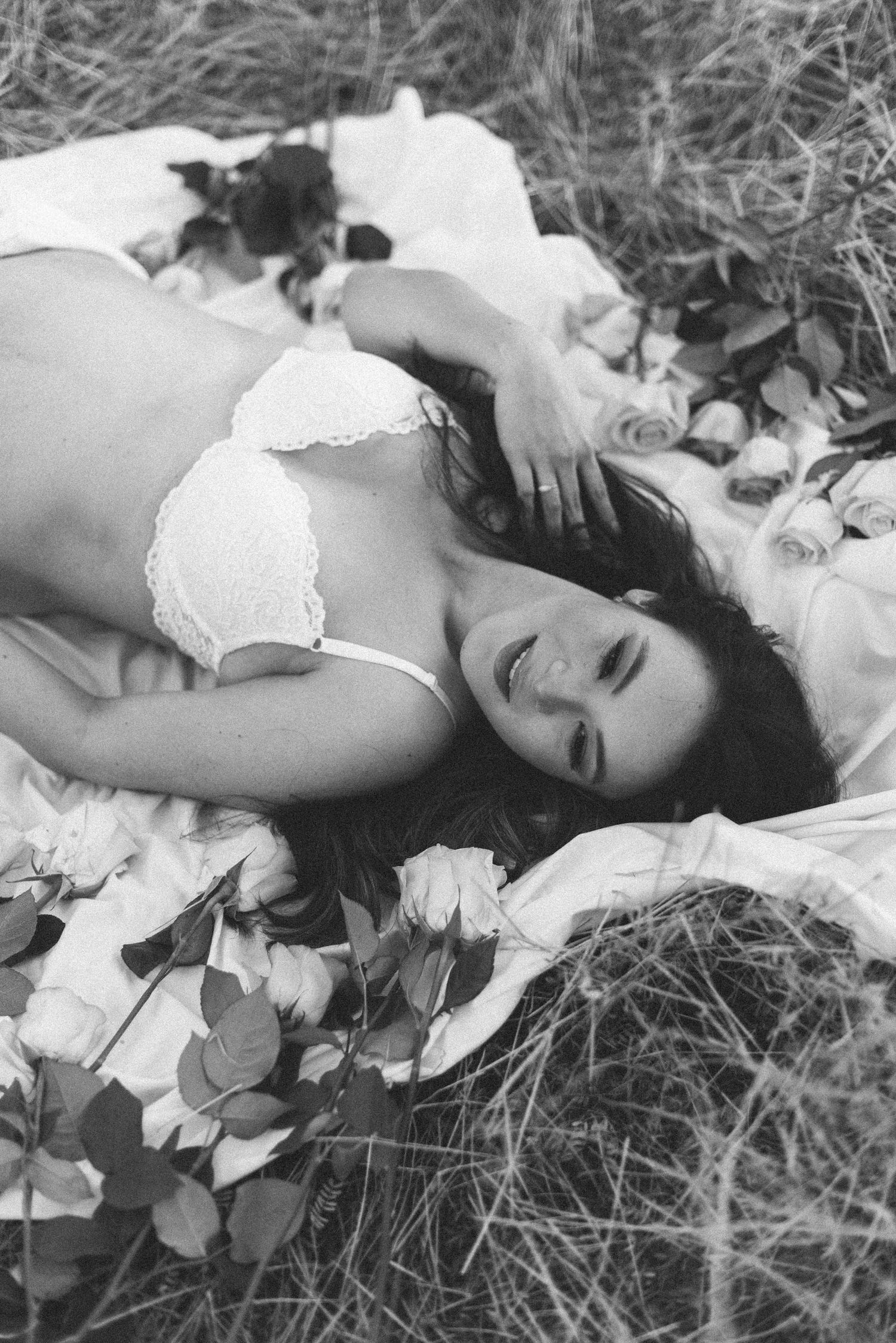 Artistic black and white maternity boudoir photo with scattered flowers.