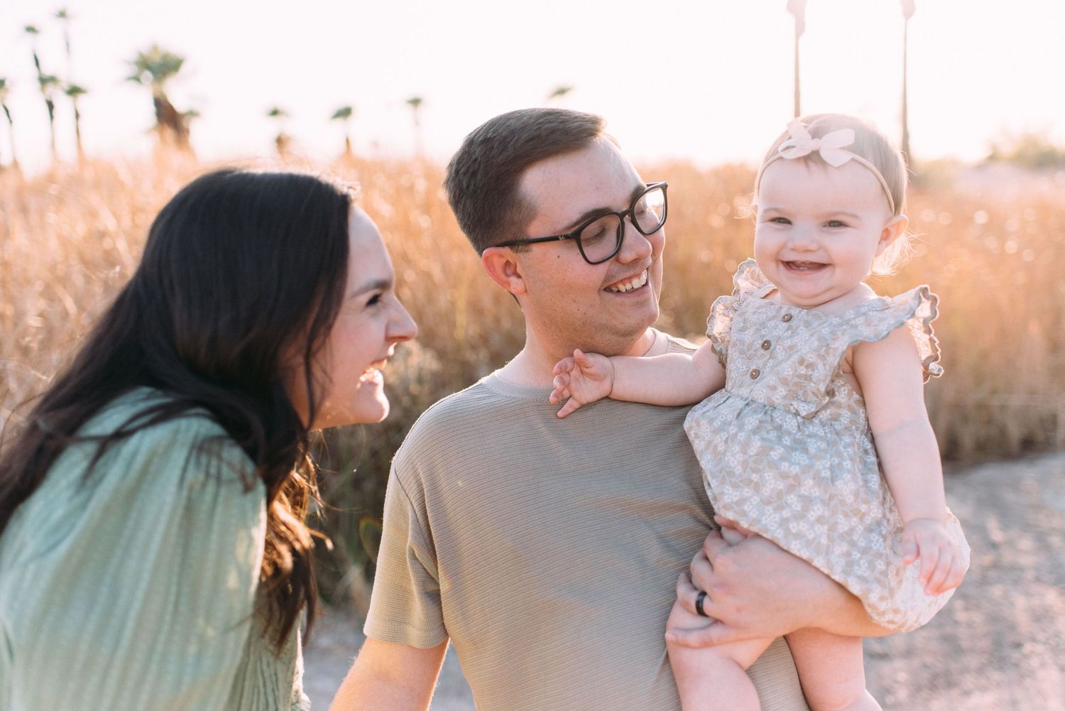 A family laughs together while posing for photos on a sunset-lit pathway.