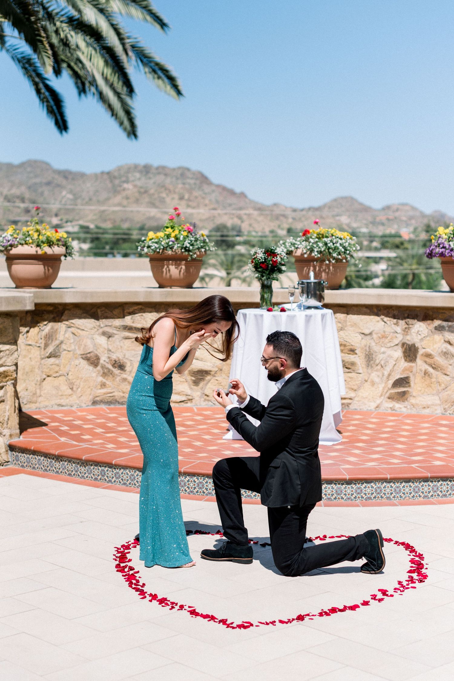 Surprise proposal moment captured on elegant terrace with mountain views.