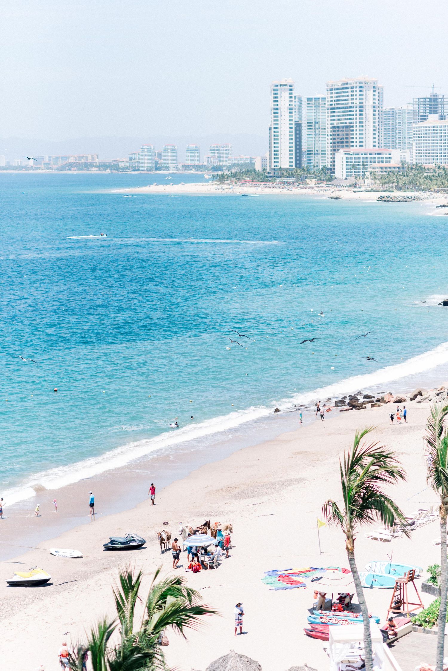 Beachfront view of high-rise buildings and tourists enjoying the sandy shore.