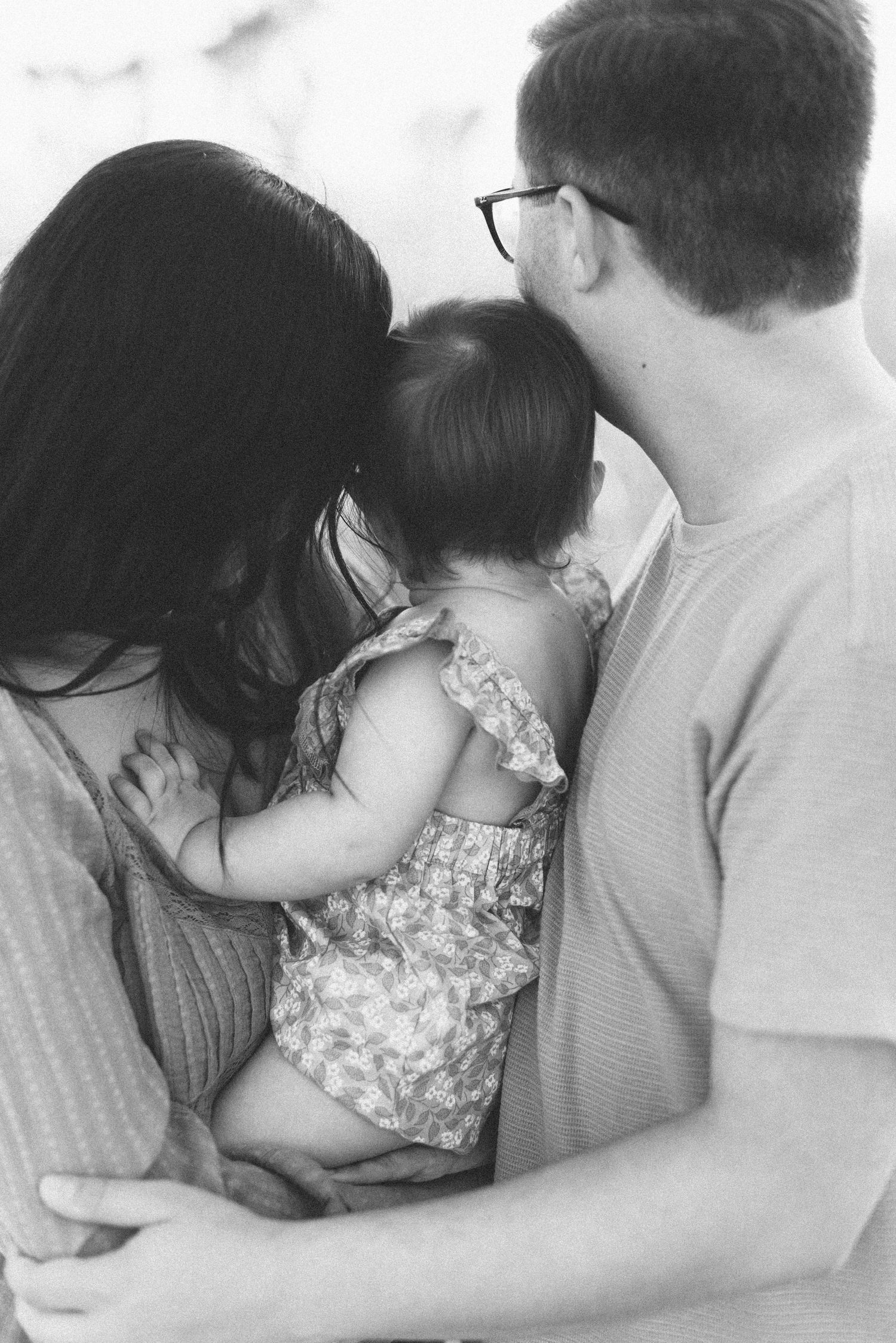 Black and white intimate family portrait showing tender embrace outdoors.