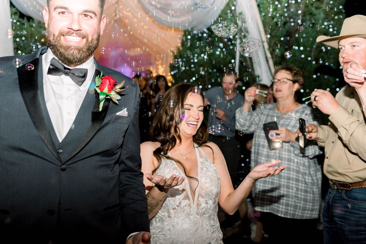 Joyous celebration with confetti falling during wedding reception under draped tent.