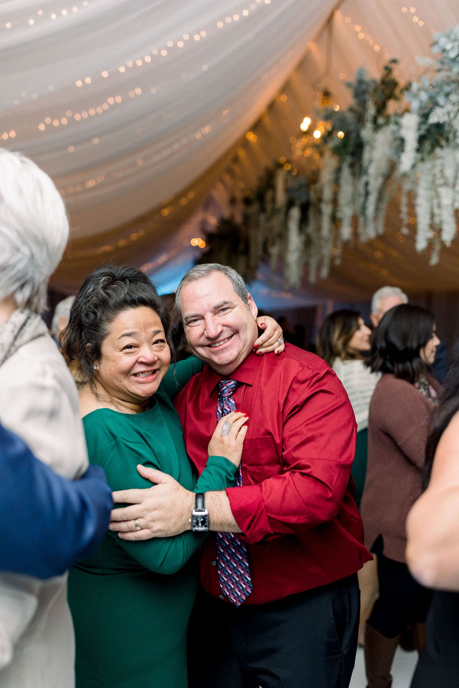 Wedding guests share joyful embrace during reception celebration.