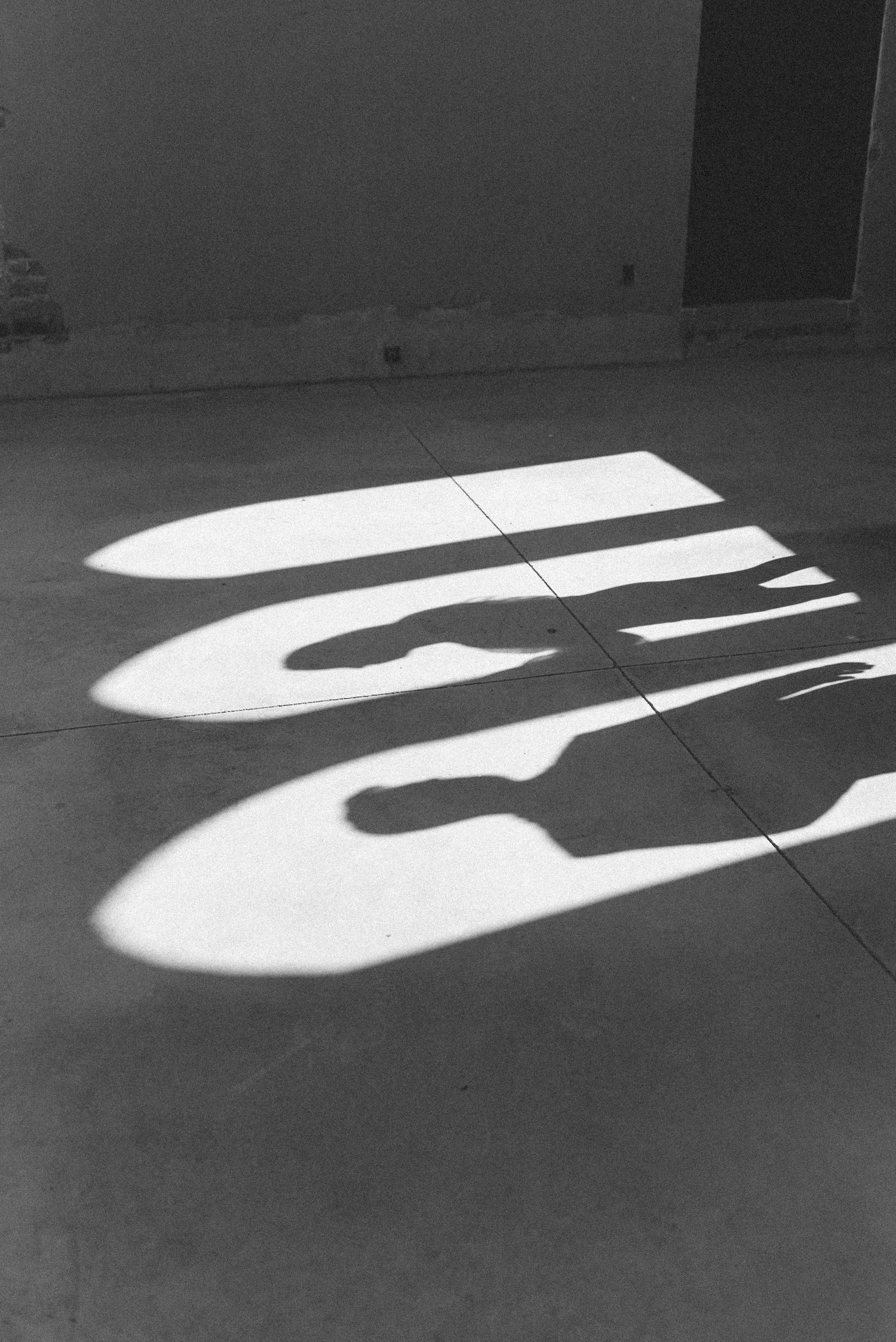 Artistic black and white shadow patterns cast on a concrete floor.