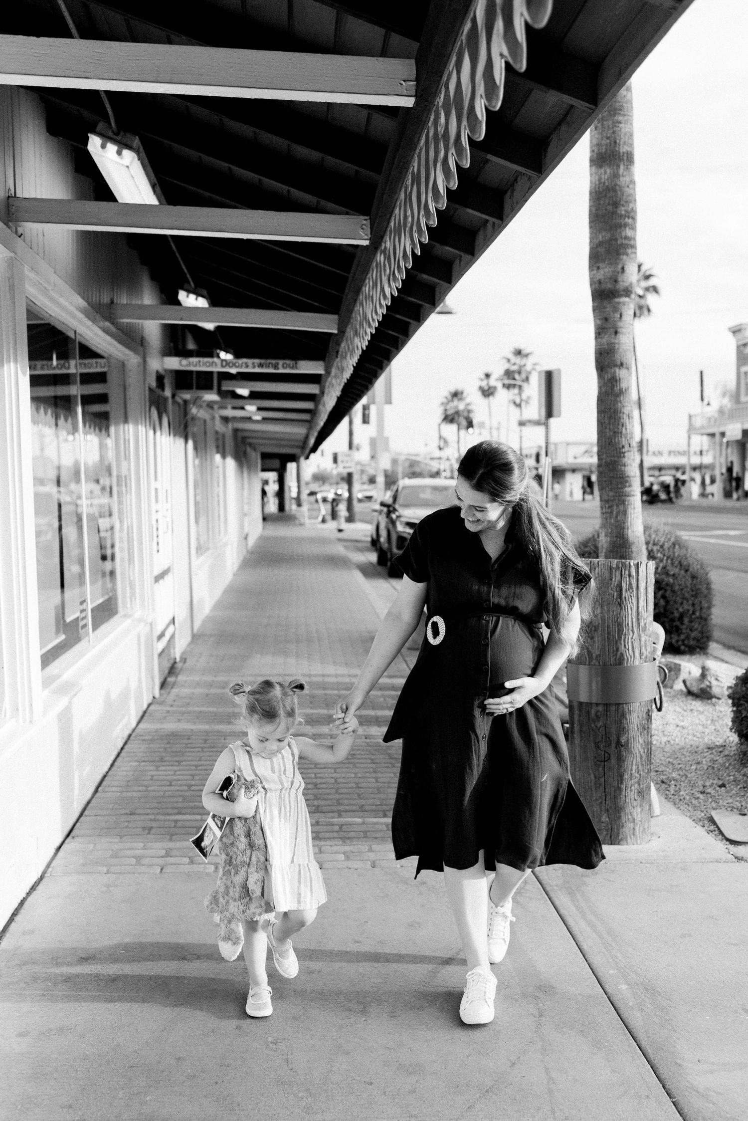 Black and white photo series showing people walking and sitting under covered walkway with palm trees.