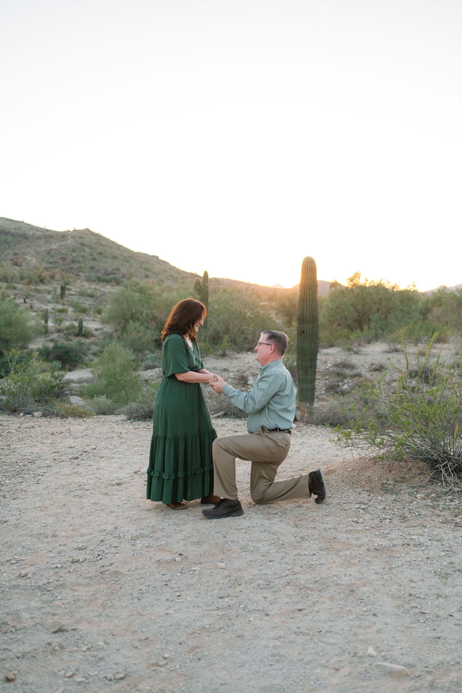 A romantic proposal scene unfolds in a desert setting with saguaro cacti and golden sunlight.