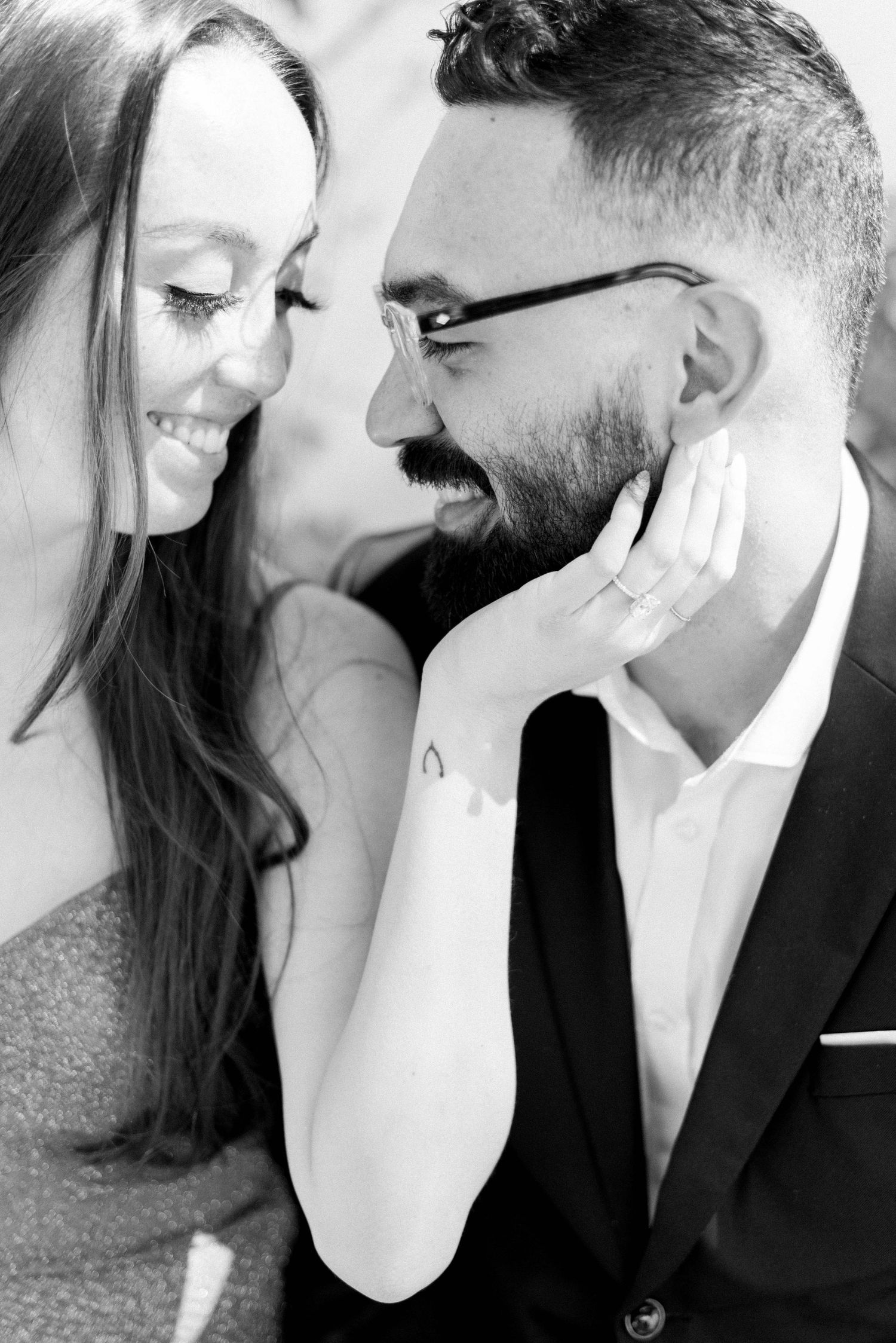 Close up black and white portrait of a couple sharing an intimate moment while smiling.