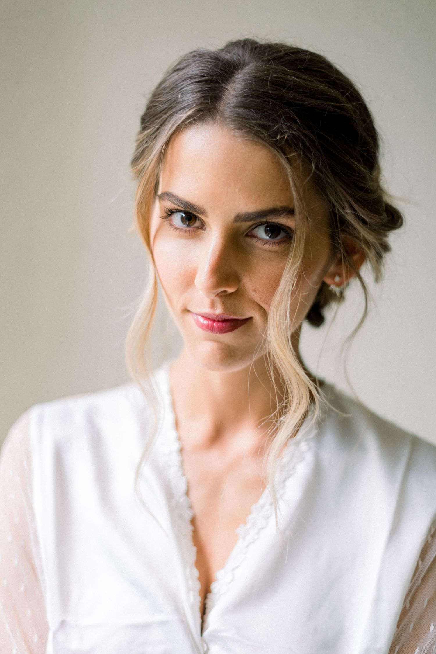 Portrait of a woman in a white robe with an elegant updo hairstyle and natural makeup.