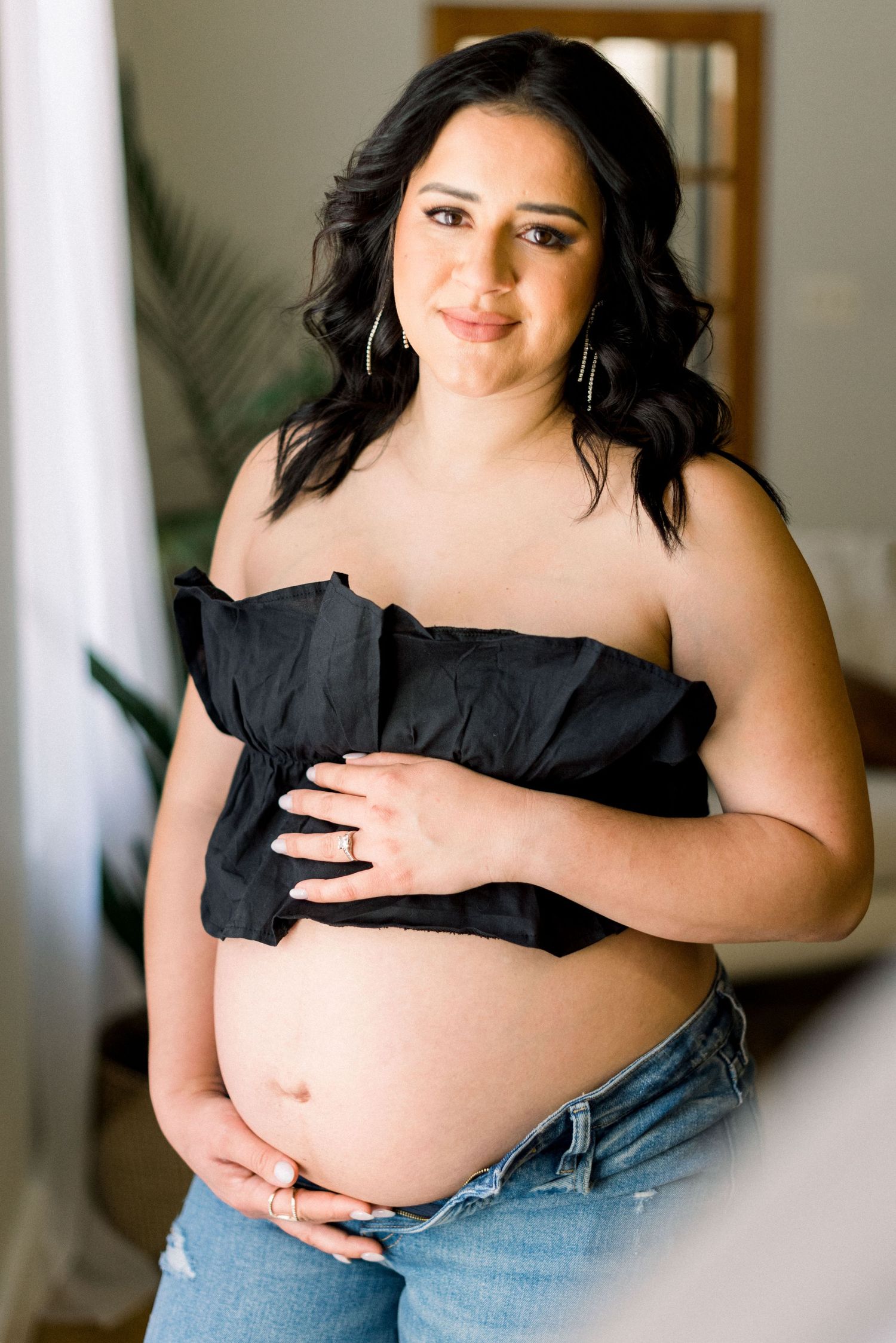 Maternity portrait showing woman in black top and jeans.
